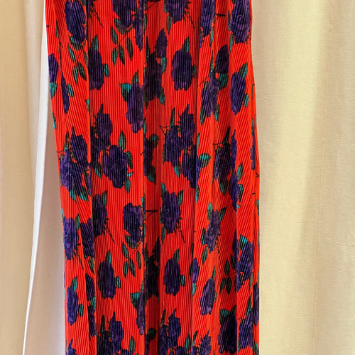Red pleated skirt with purple floral pattern on a beige background