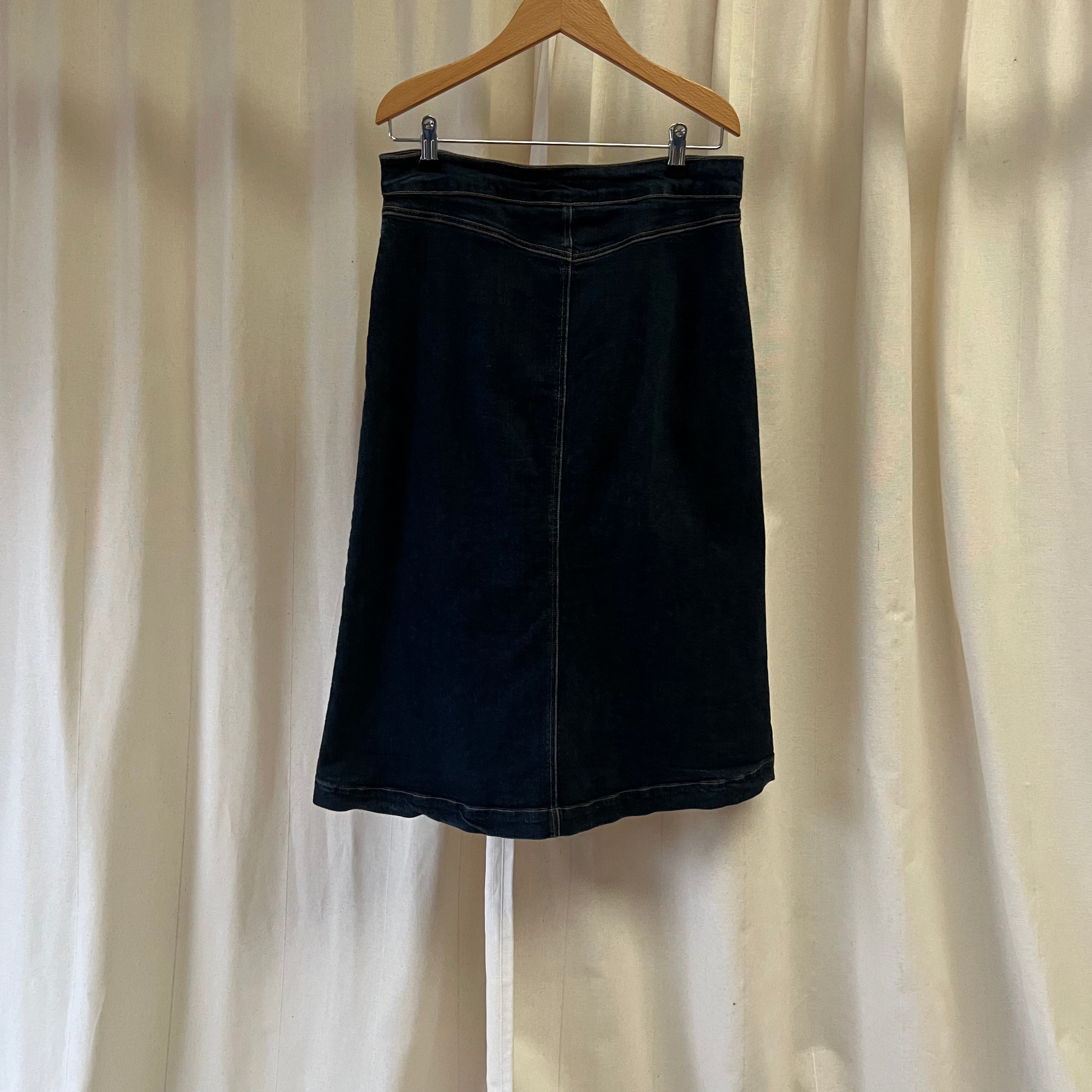 Black skirt on a hanger against a plain background