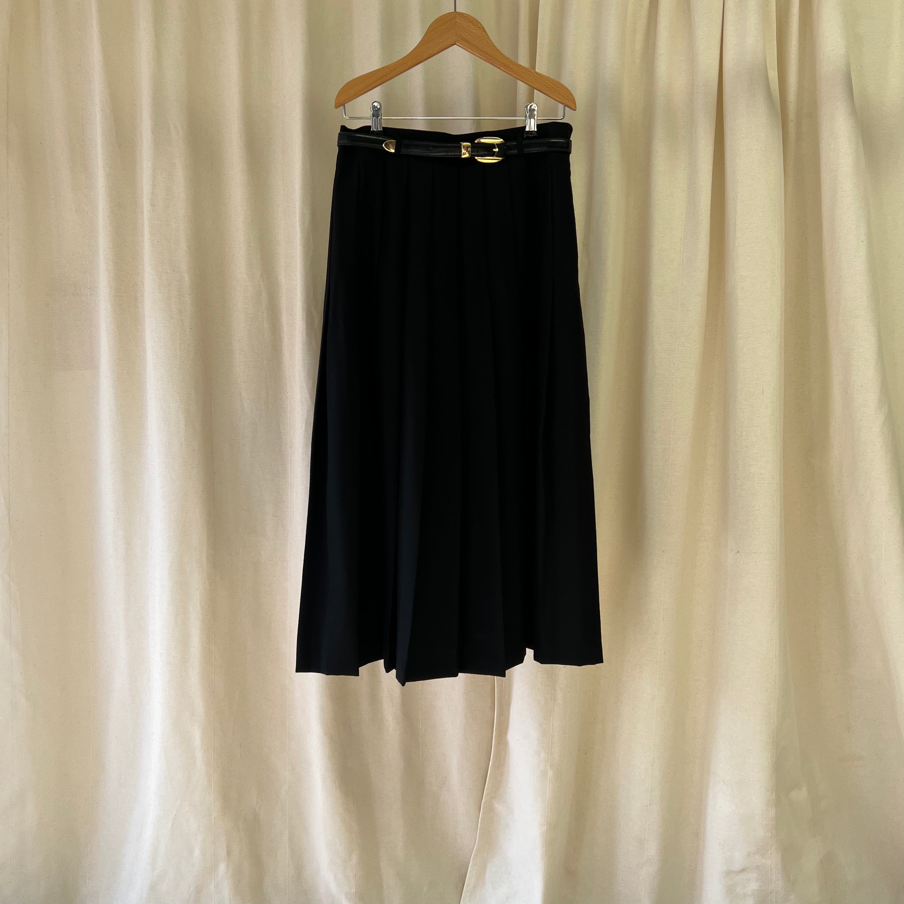 Black skirt on a hanger against a beige curtain background