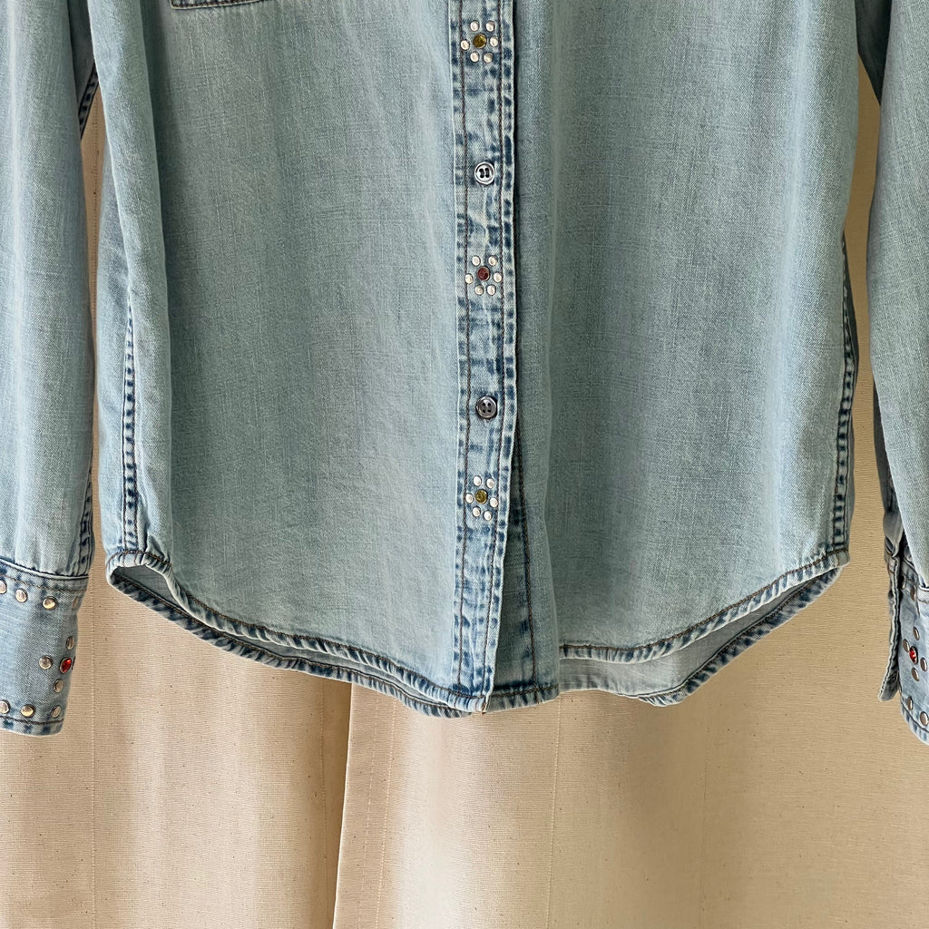 Light blue denim shirt with button details on a beige background