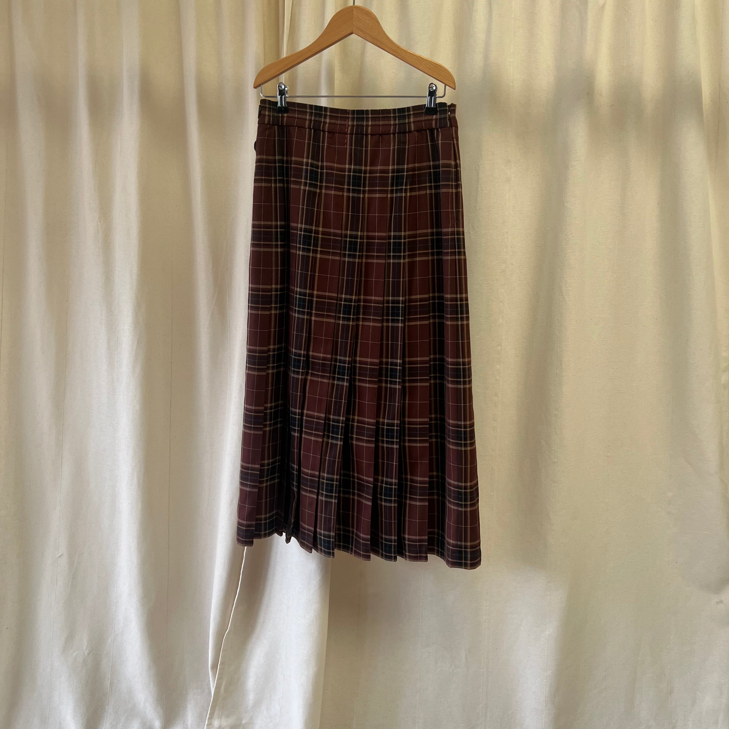 Plaid skirt on a hanger against a plain background