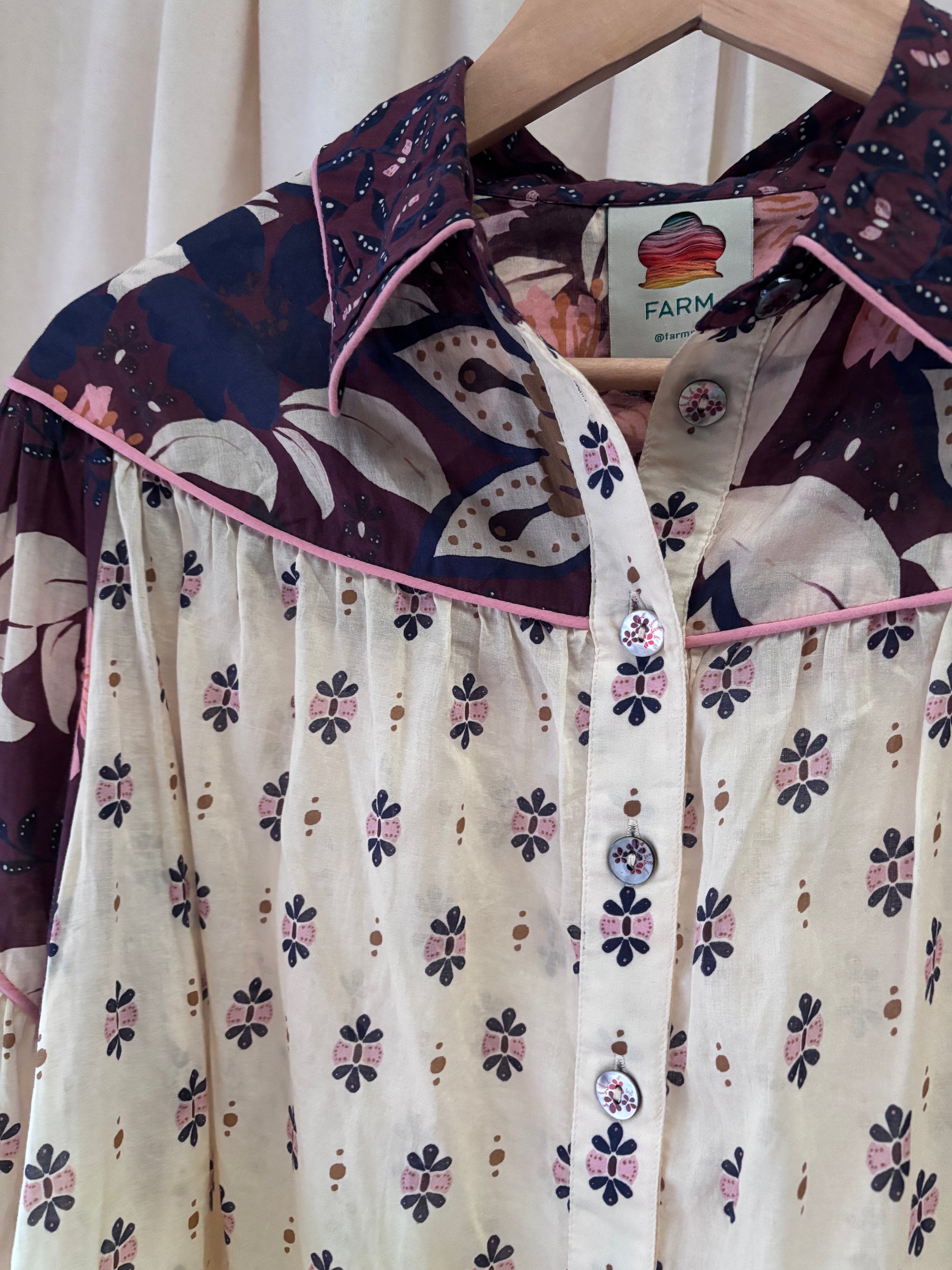 Floral patterned shirt on a hanger with visible brand tag.