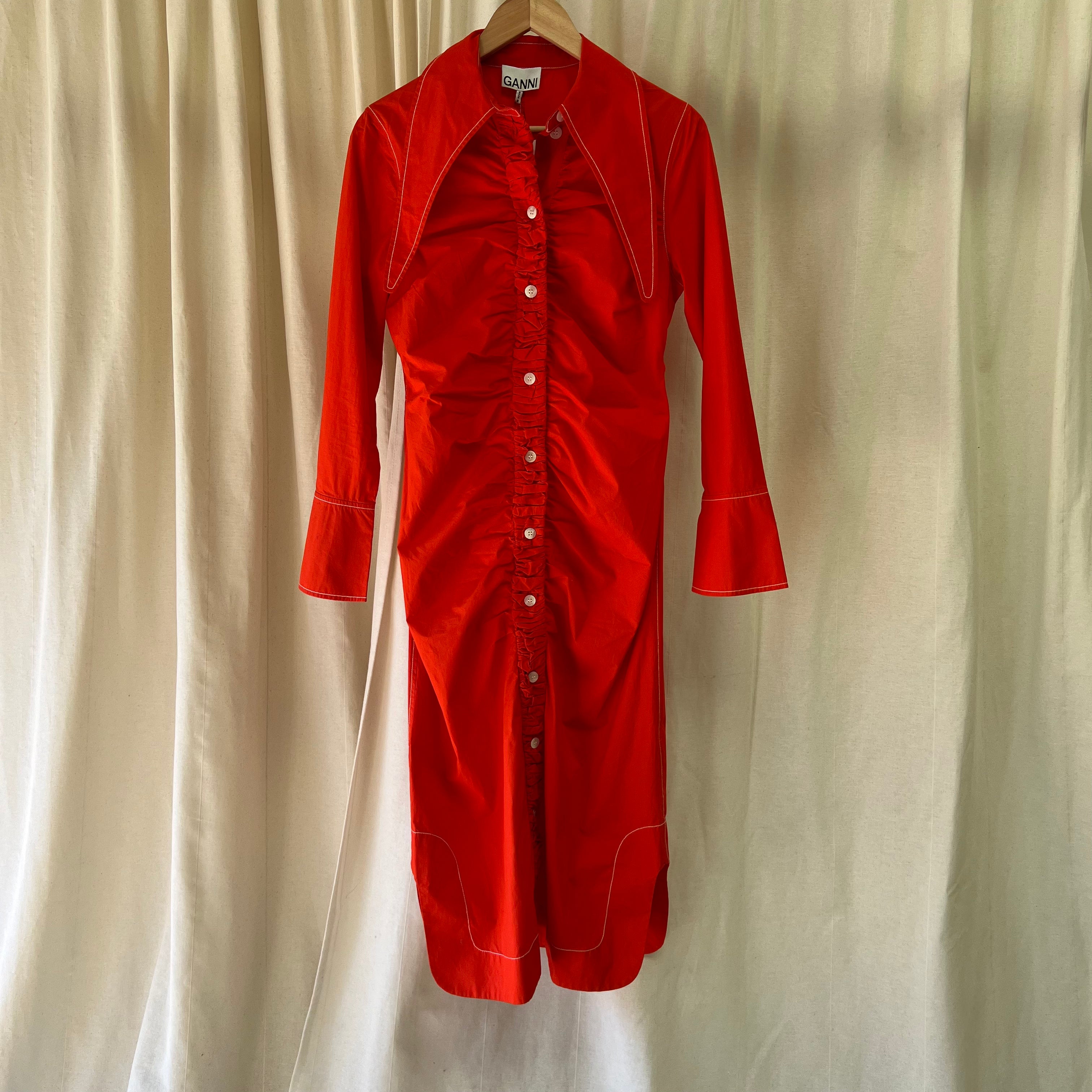 Red dress on a hanger against a beige curtain background