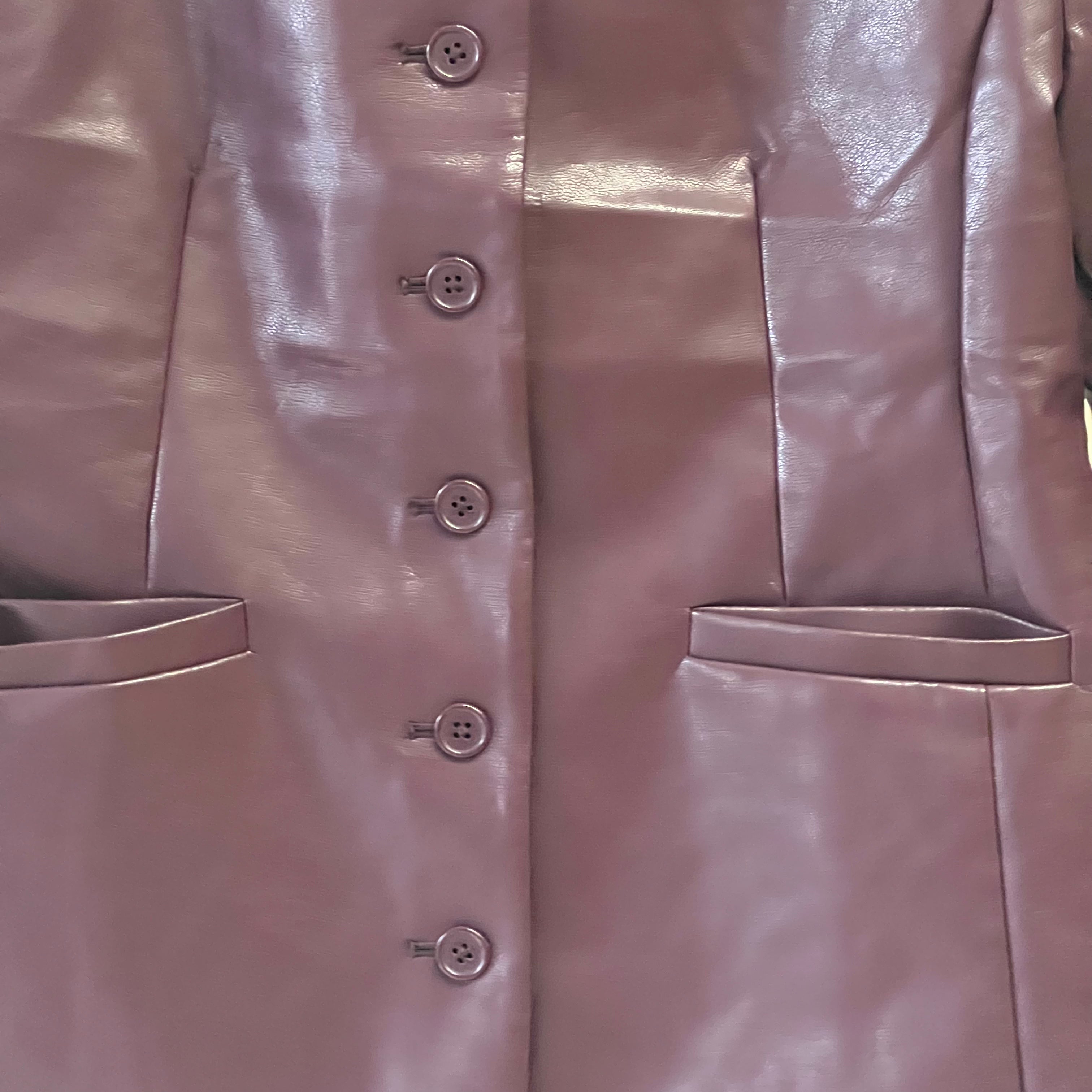 Close-up of a shiny pink coat with buttons and pockets.