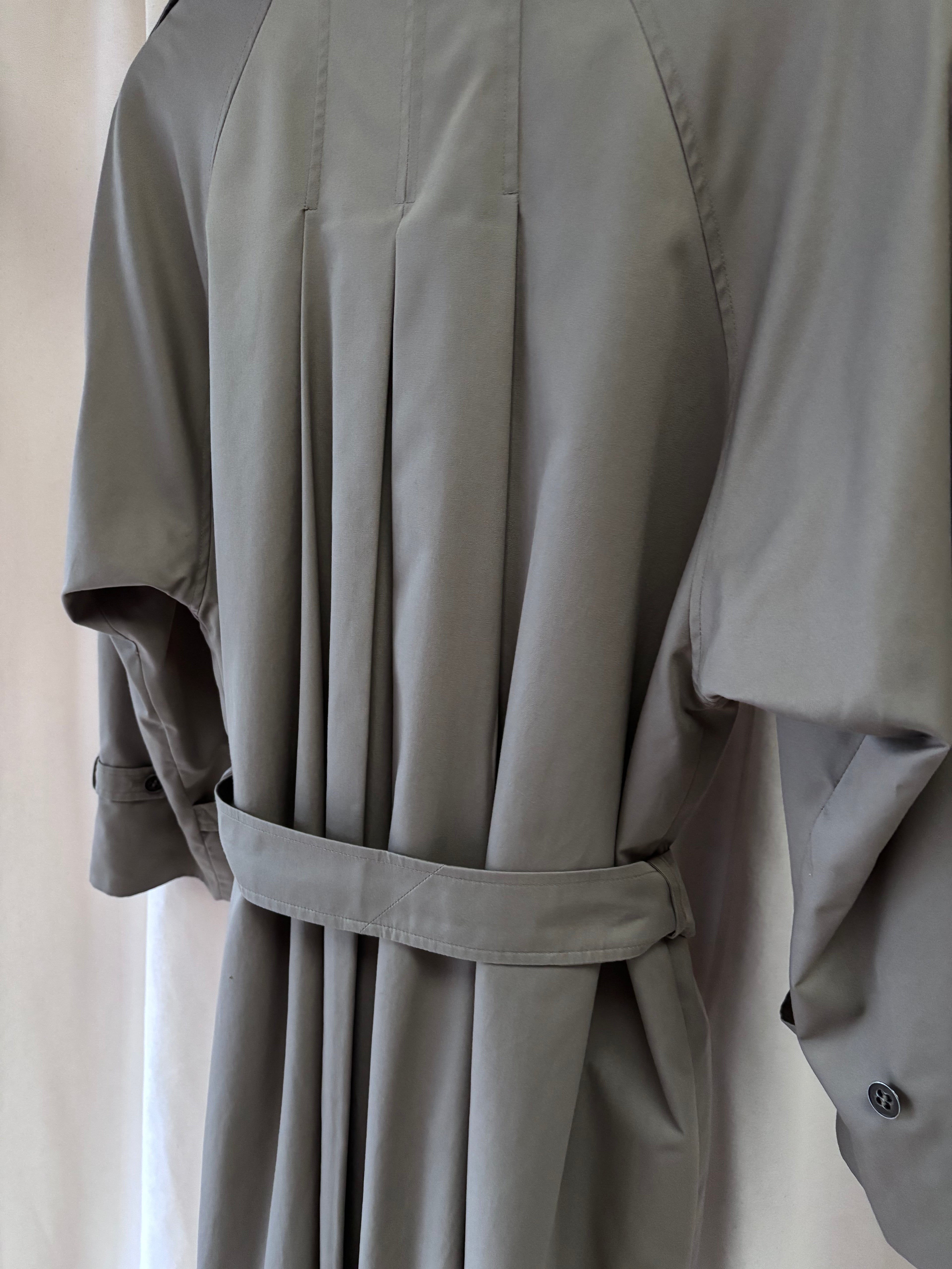 Grey trench coat with a belt on a neutral background