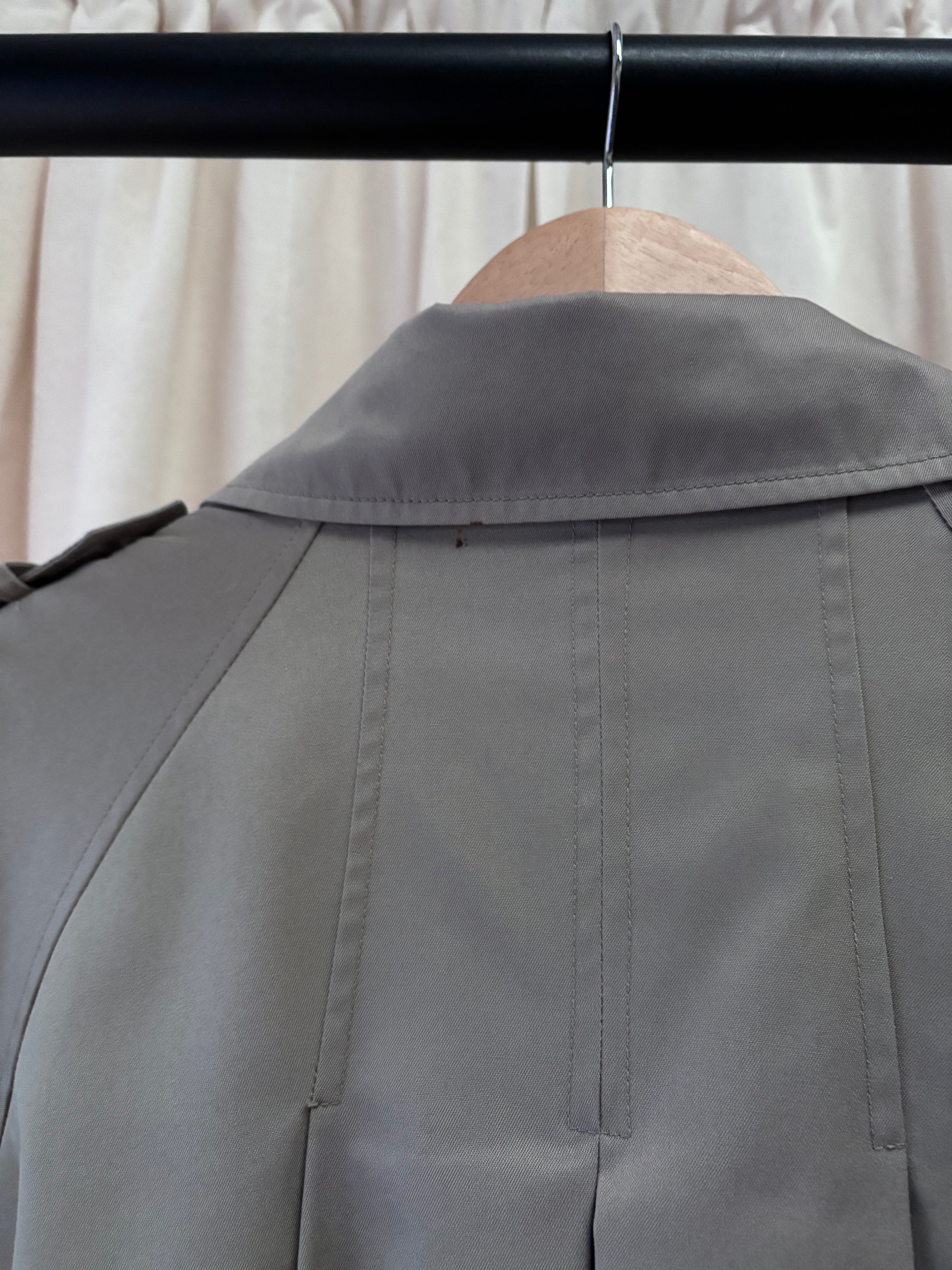 Grey jacket on a hanger against a neutral background