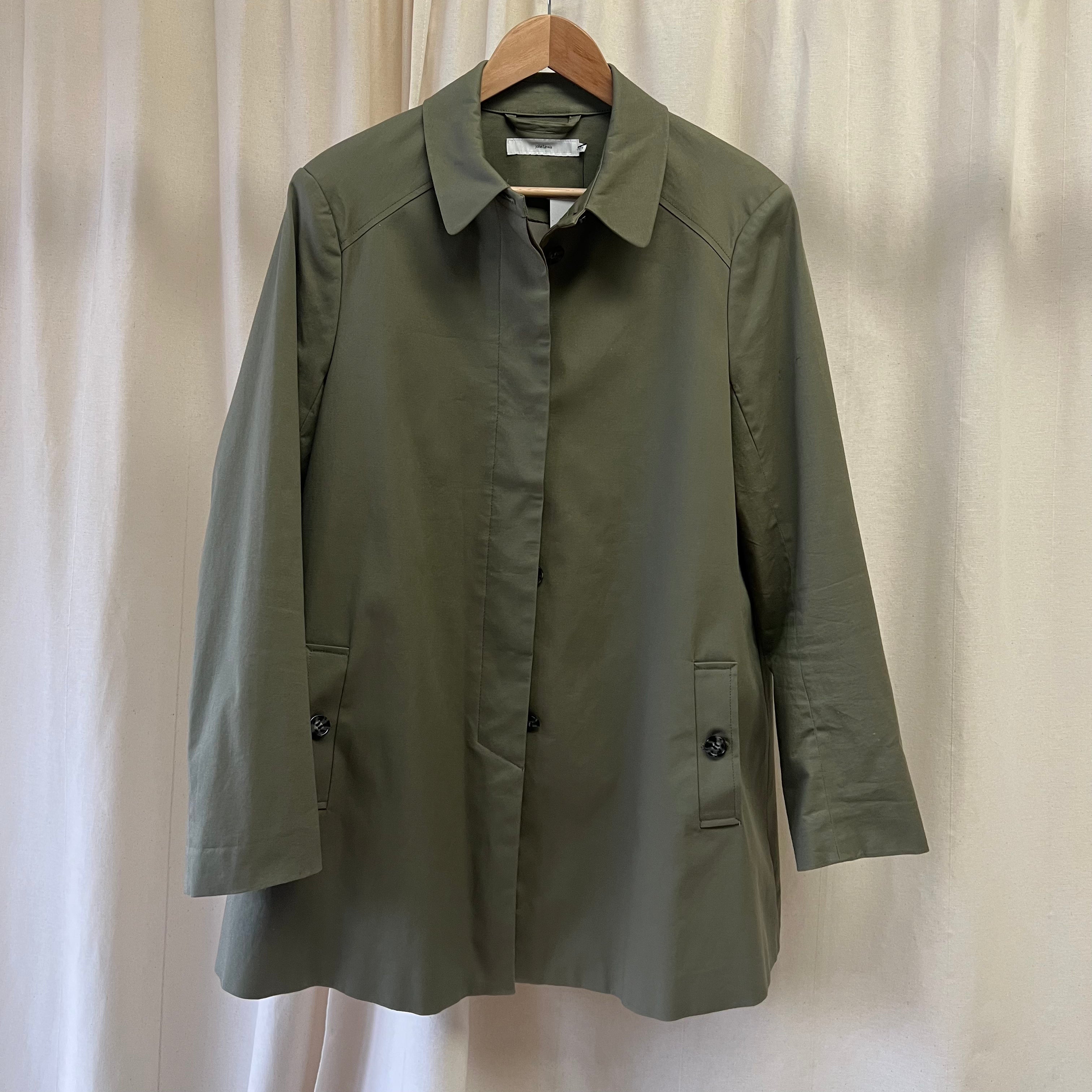 Green coat on a hanger against a white curtain background