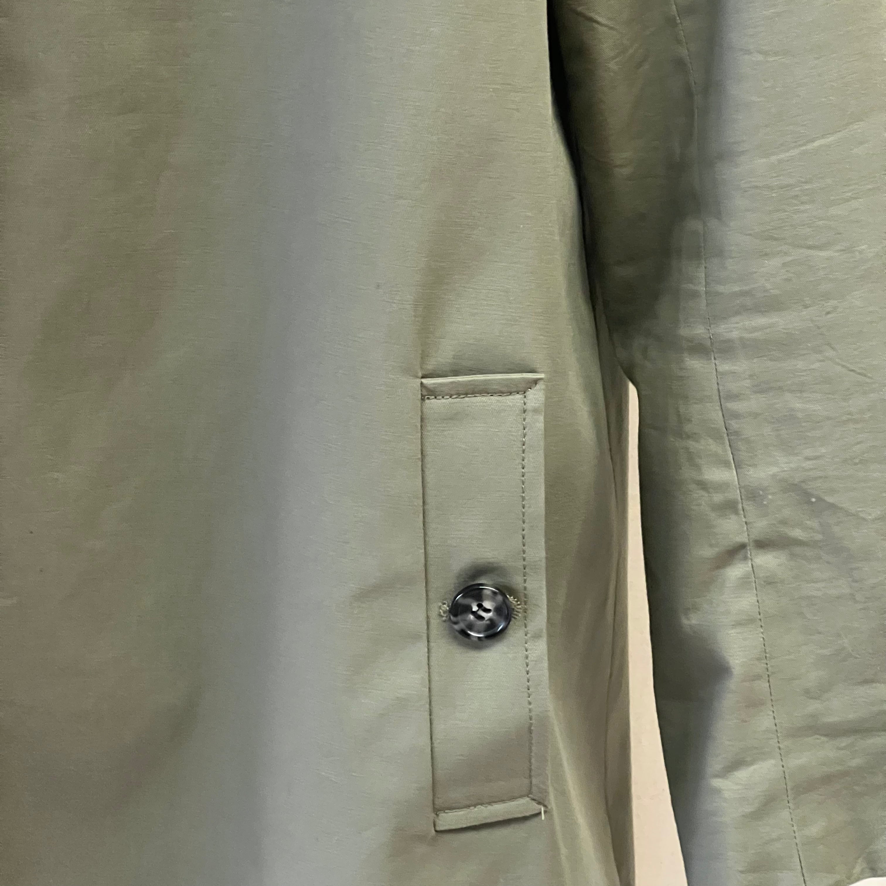 Close-up of a beige jacket with a button on a white background