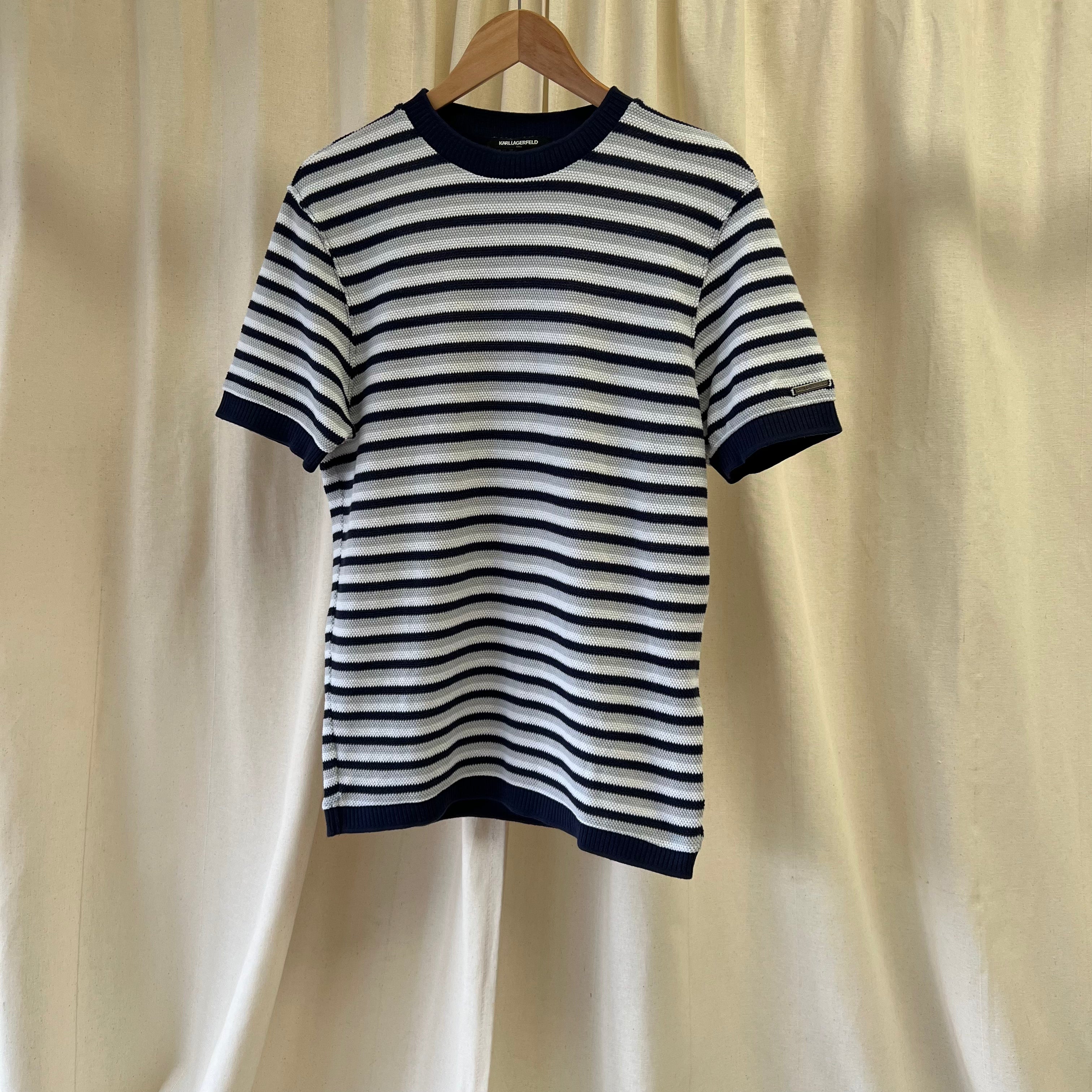 Black and white striped shirt on a hanger against a beige curtain background