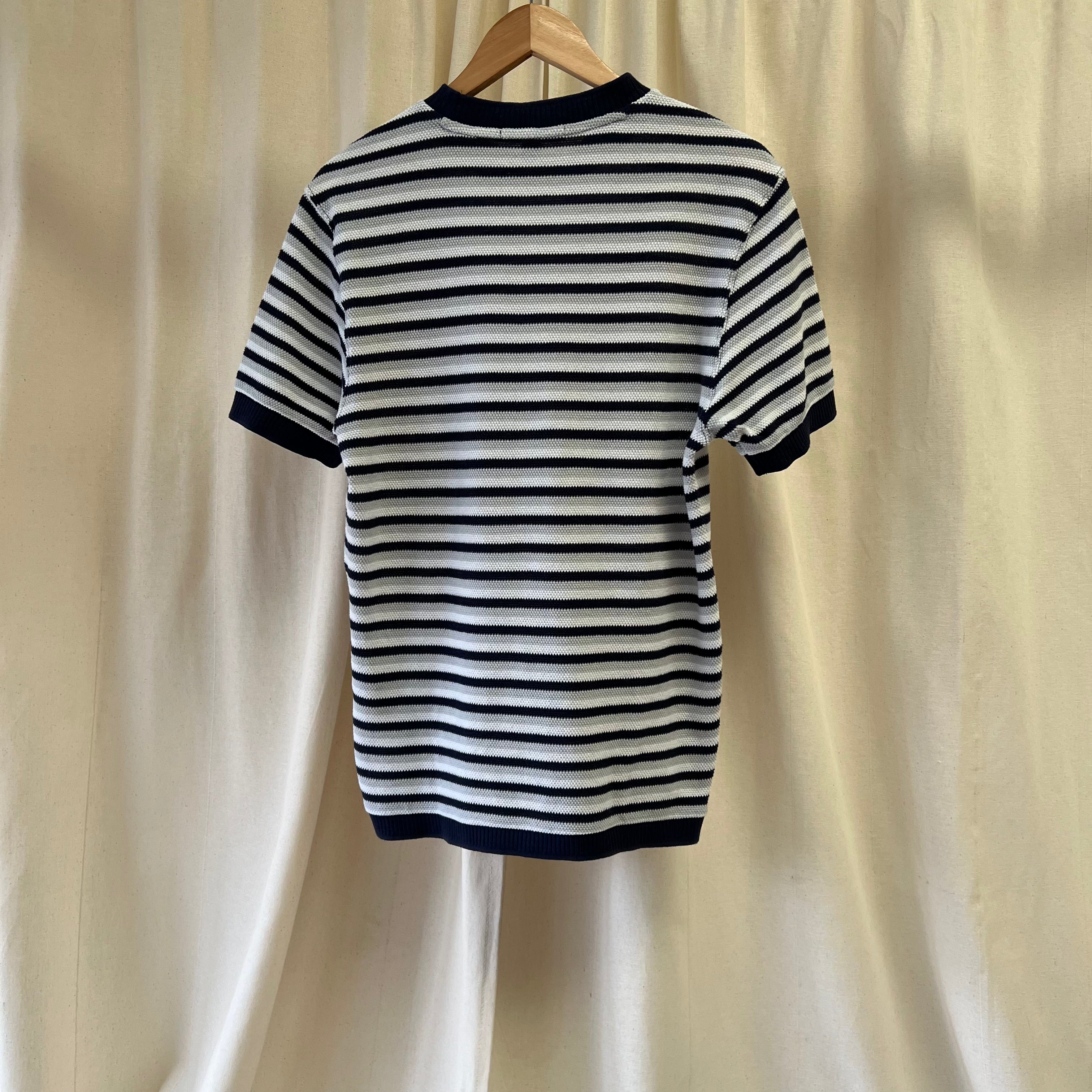 Black and white striped shirt on a hanger against a beige curtain background