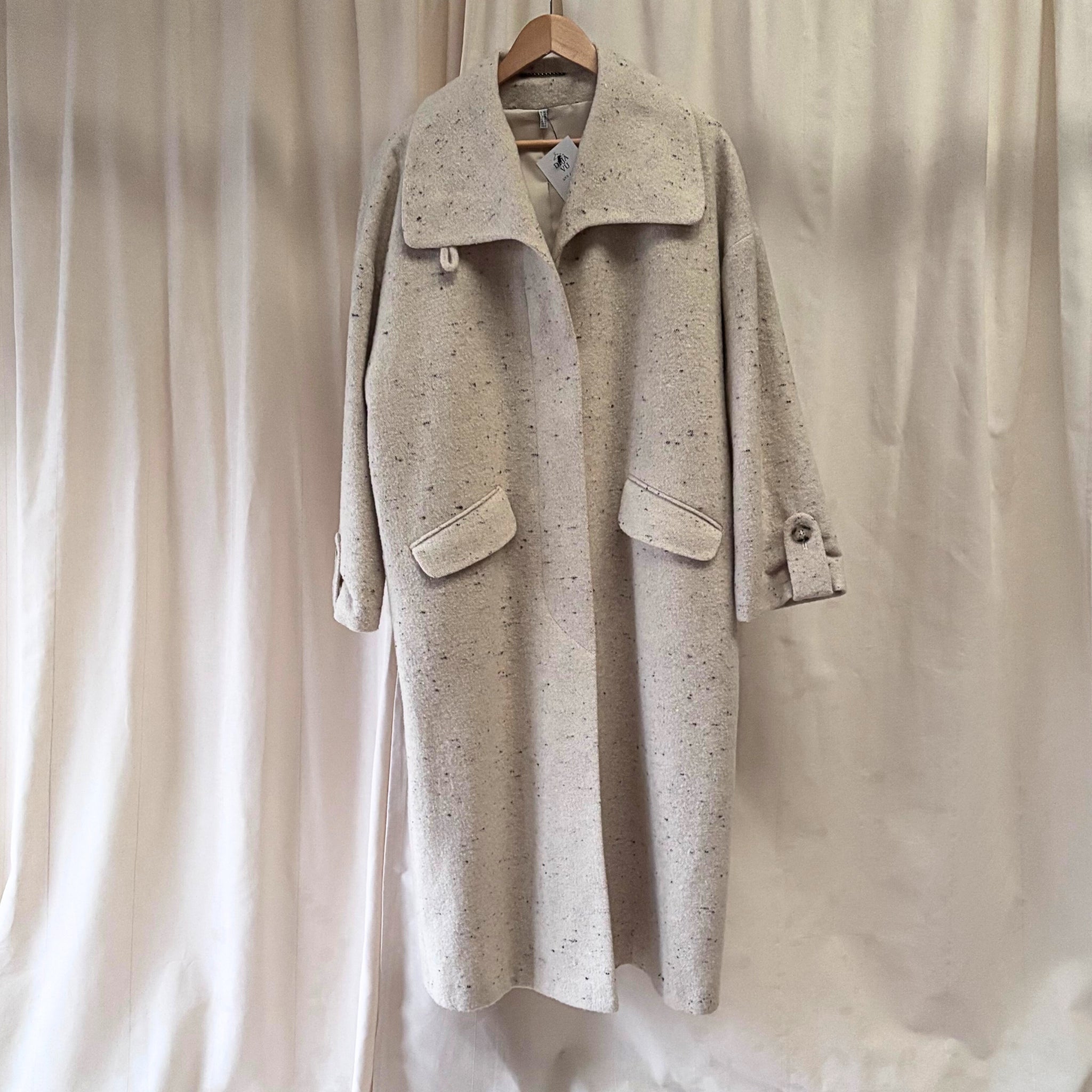 Beige coat hanging against a neutral background
