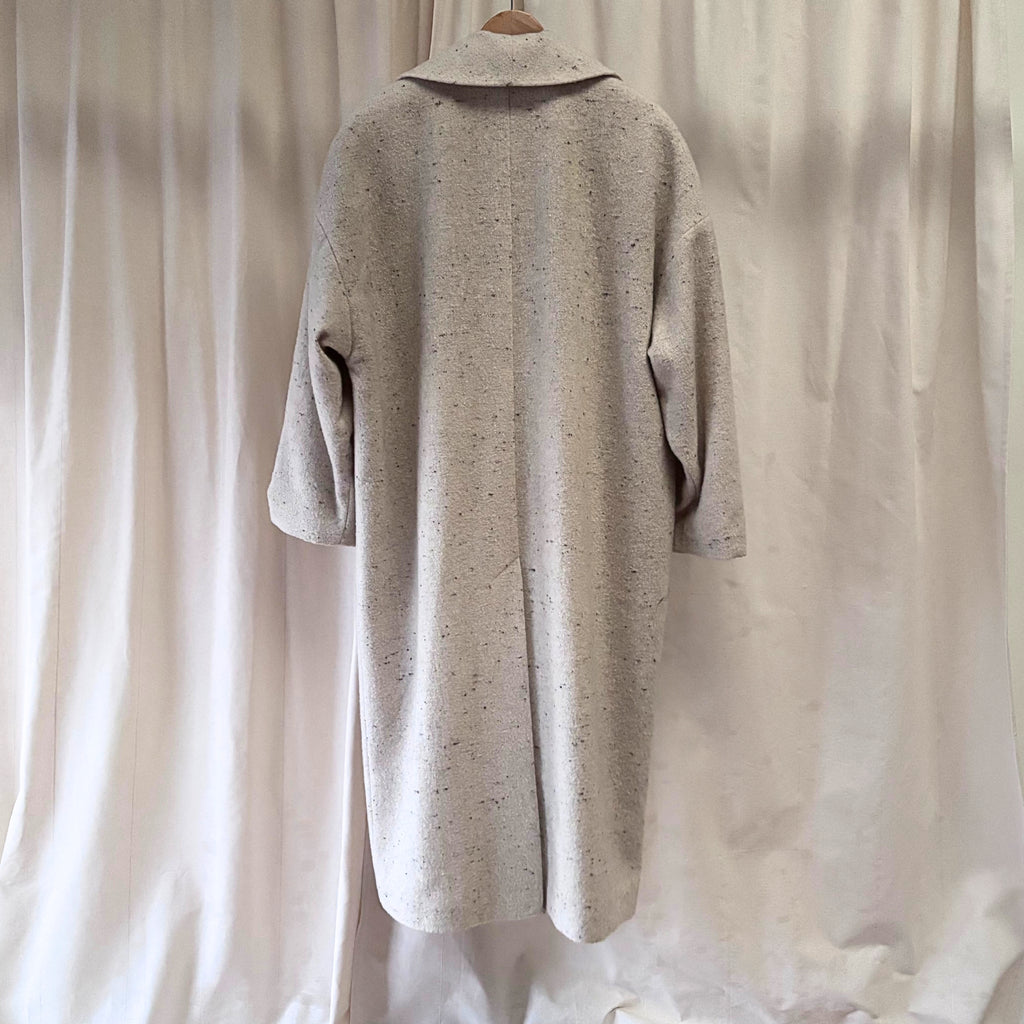 Beige coat on a hanger against a plain background