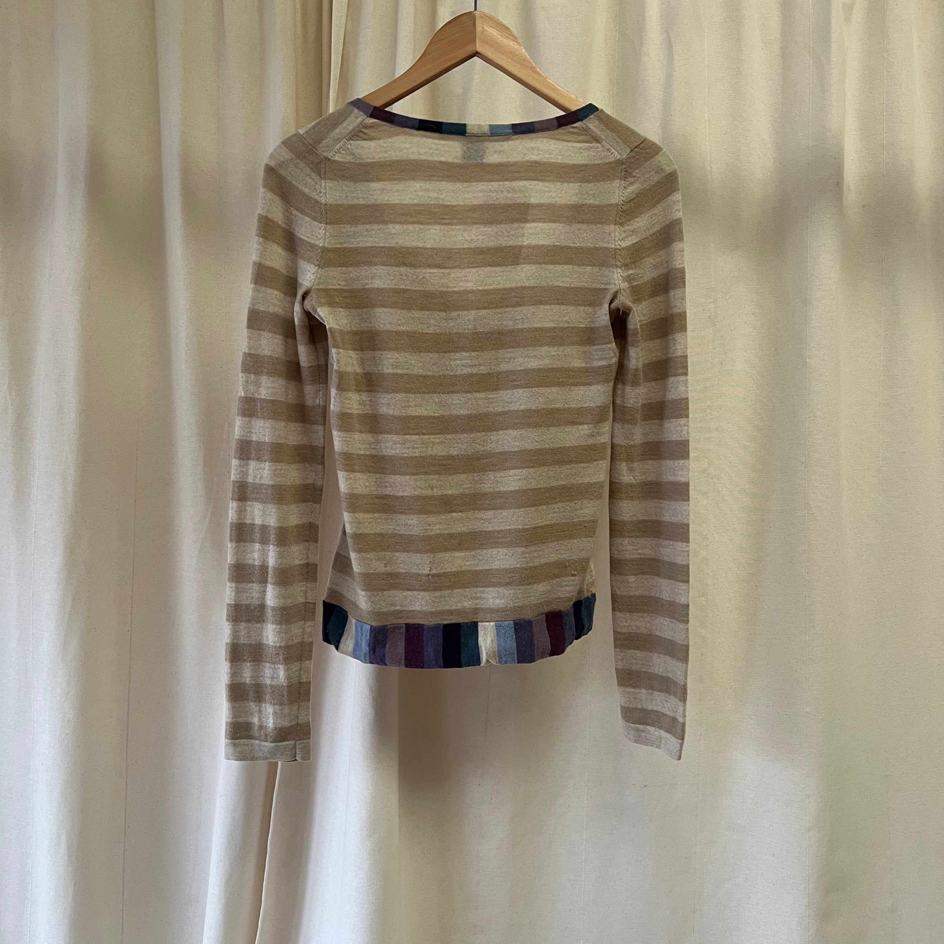 Striped sweater on a hanger against a plain background
