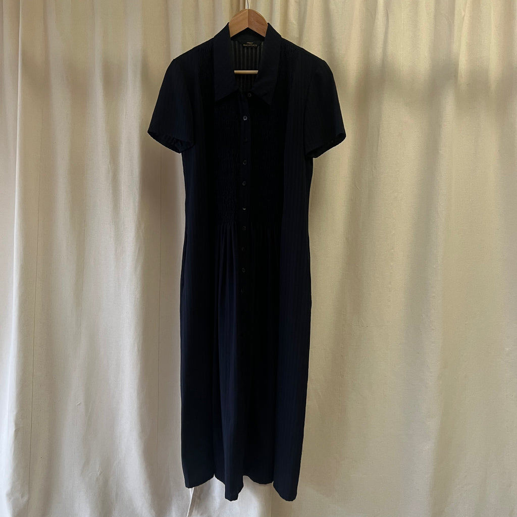 Navy dress hanging against a plain white curtain