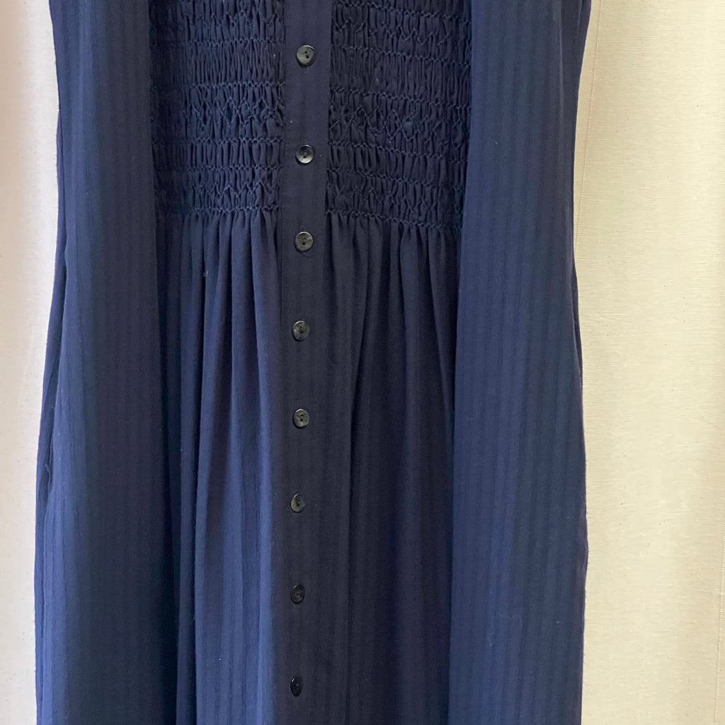 Navy blue sleeveless dress with button details on a beige background