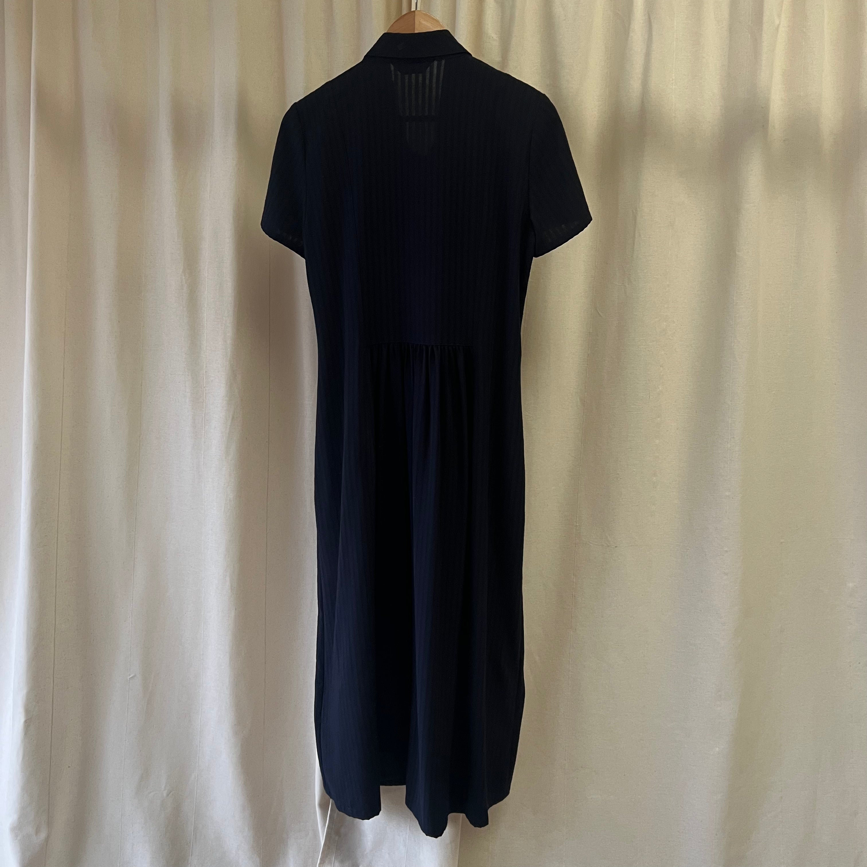 Black dress on a hanger against a beige curtain background