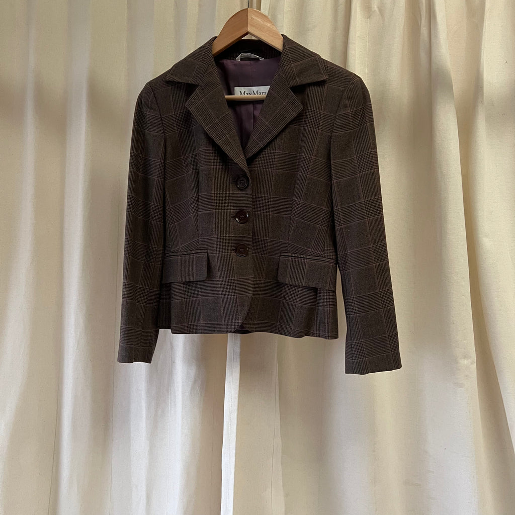 Brown checkered blazer on a hanger against a beige curtain background