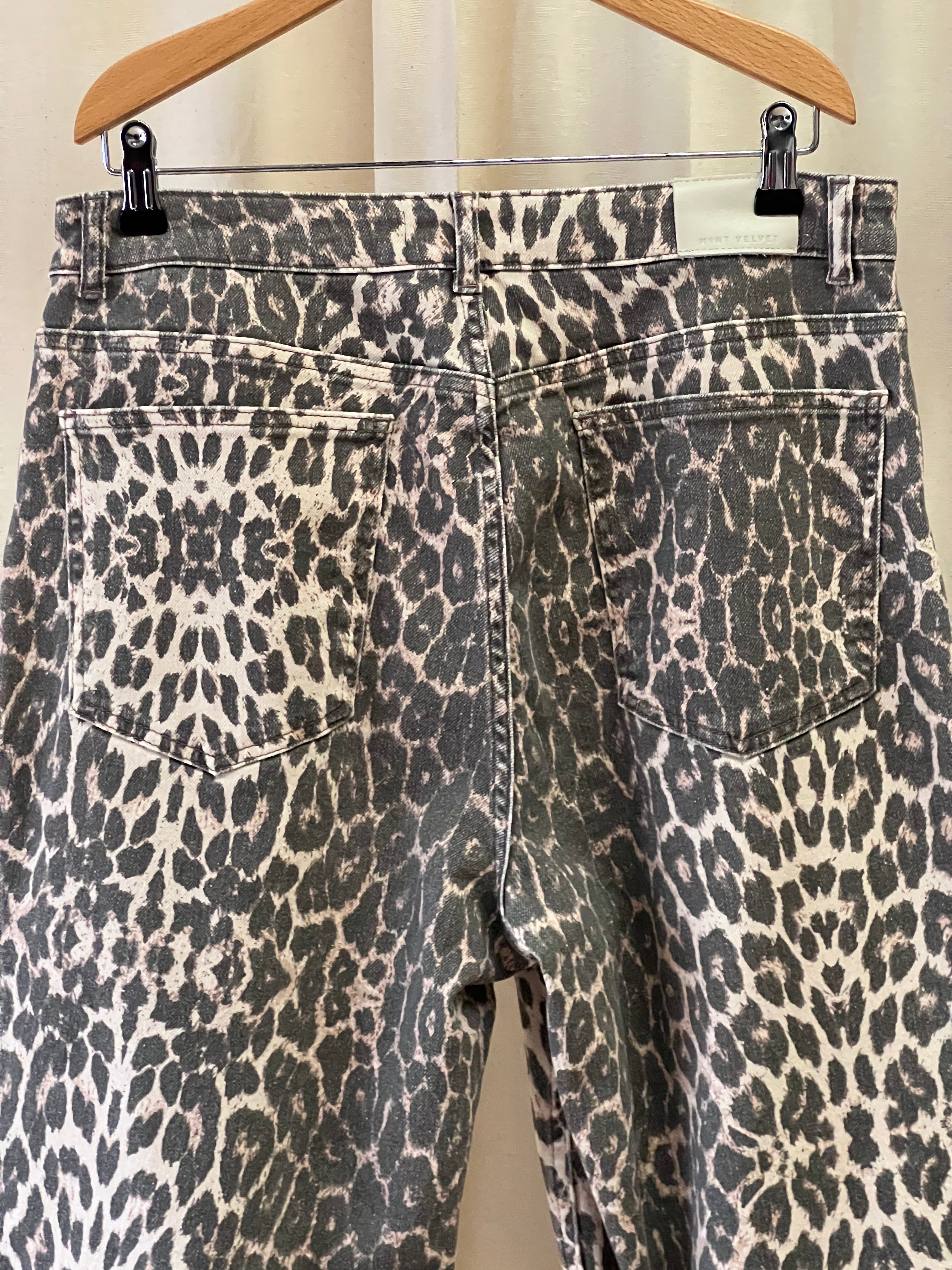Leopard print pants on a hanger against a white background