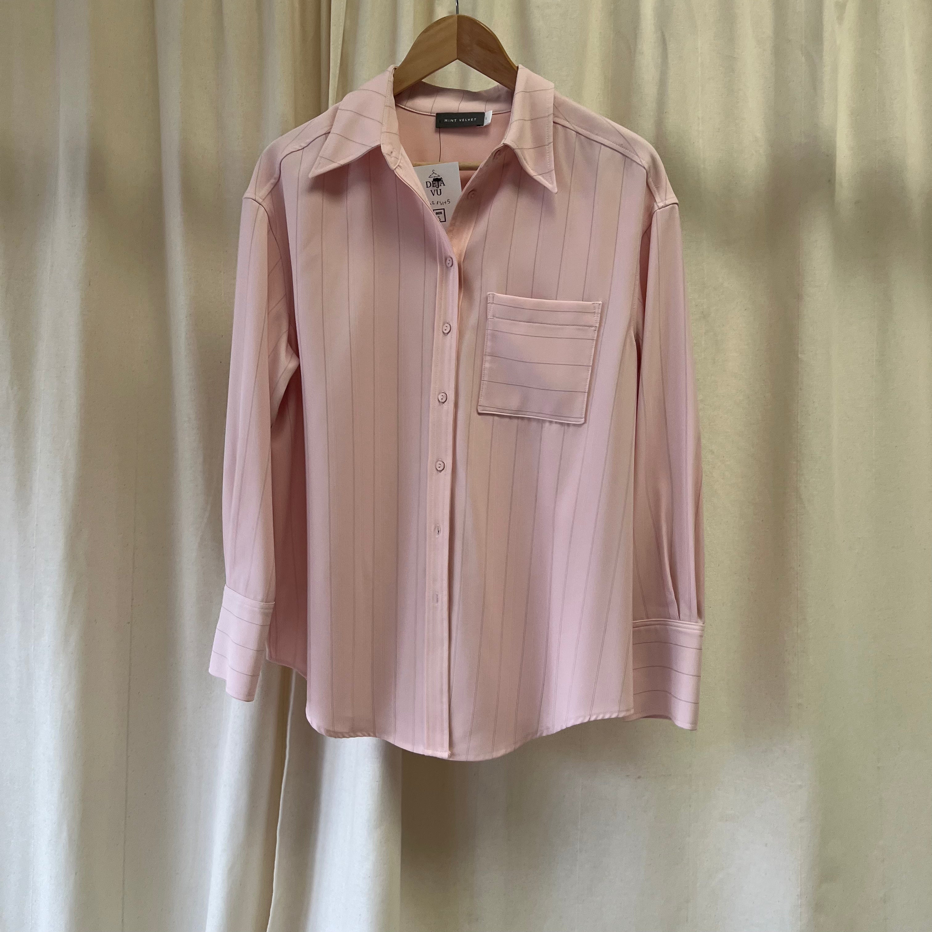 Pink striped shirt on a hanger against a beige curtain background