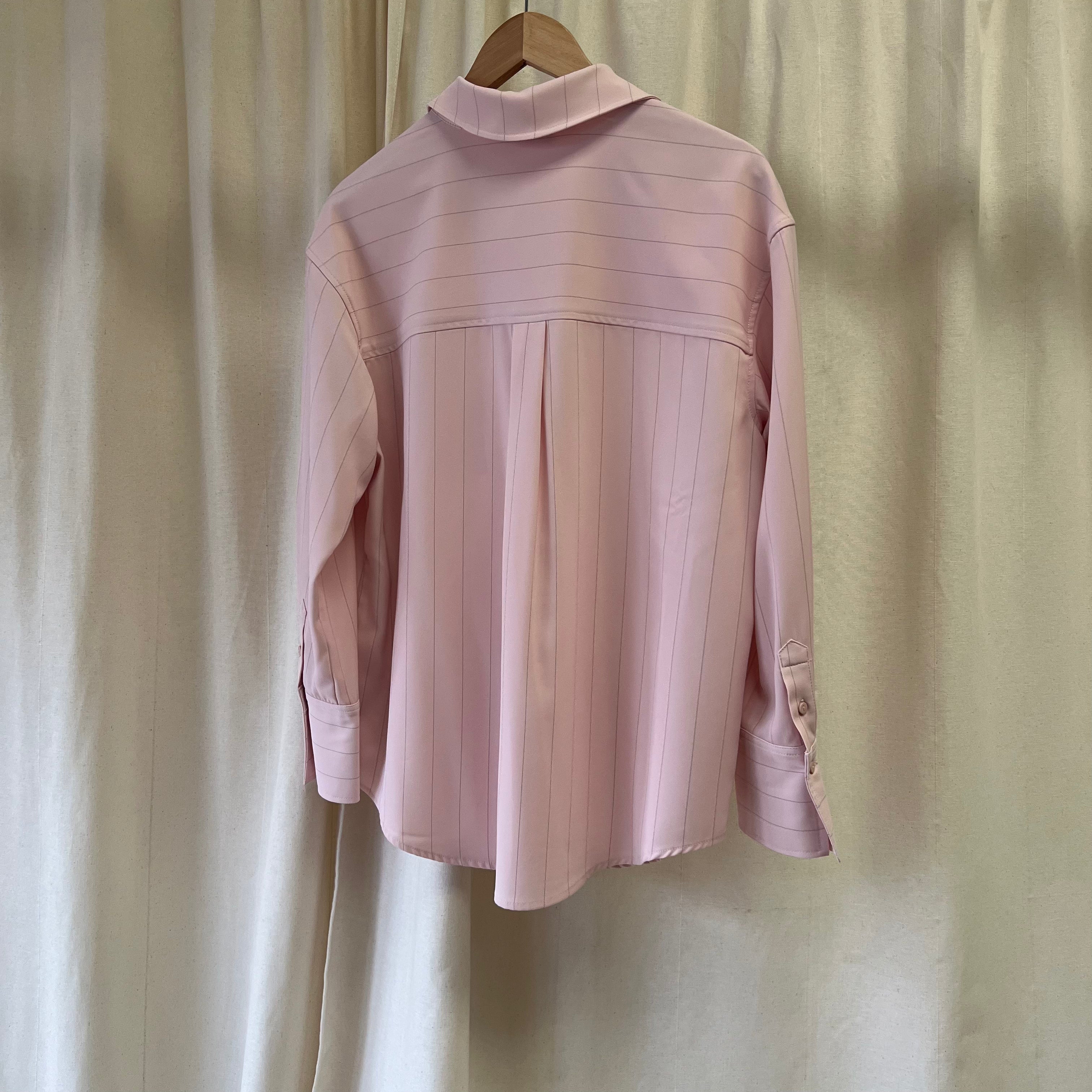 Pink blouse on a hanger against a plain background