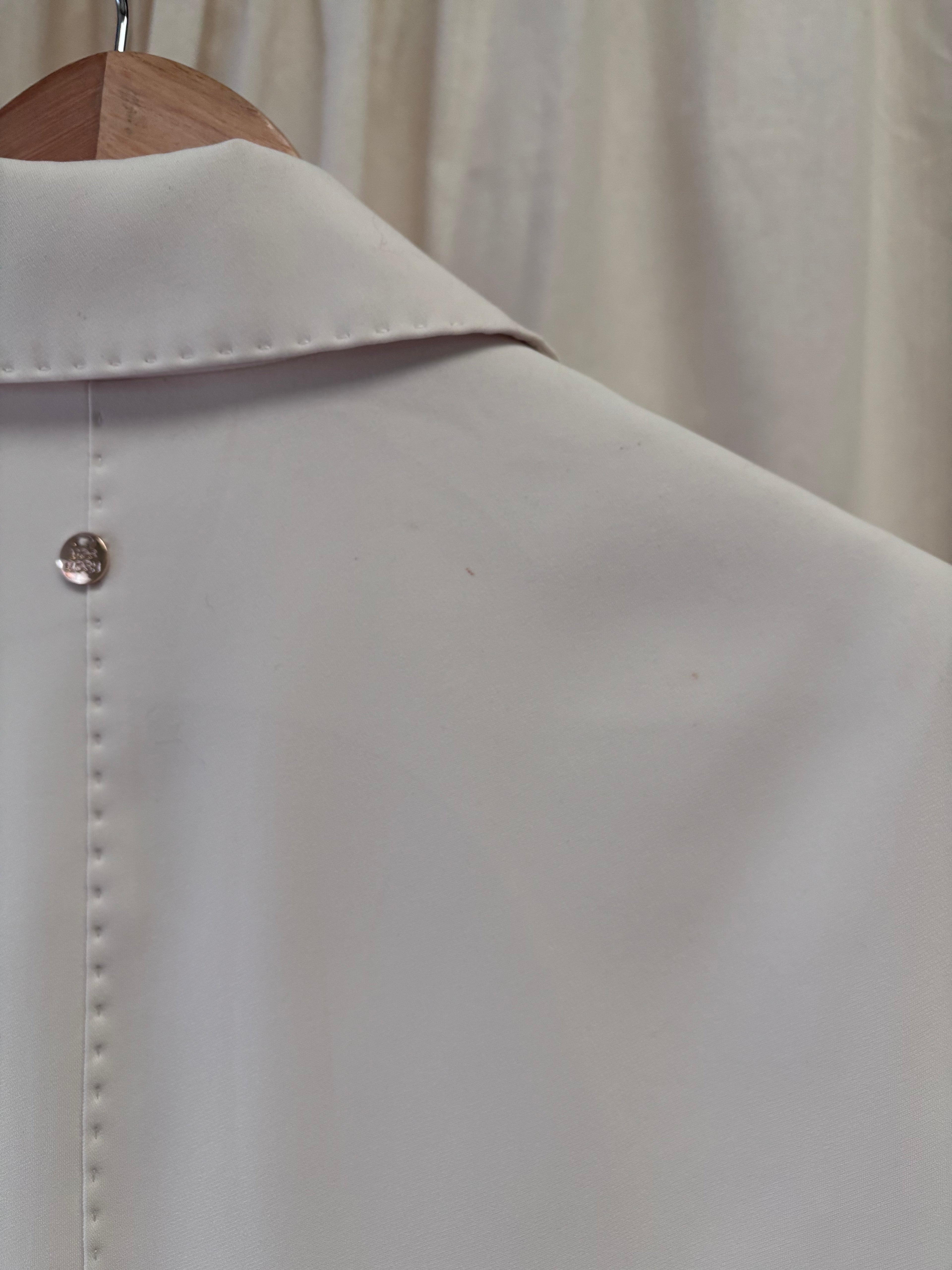 Light gray shirt on a wooden hanger against a neutral background