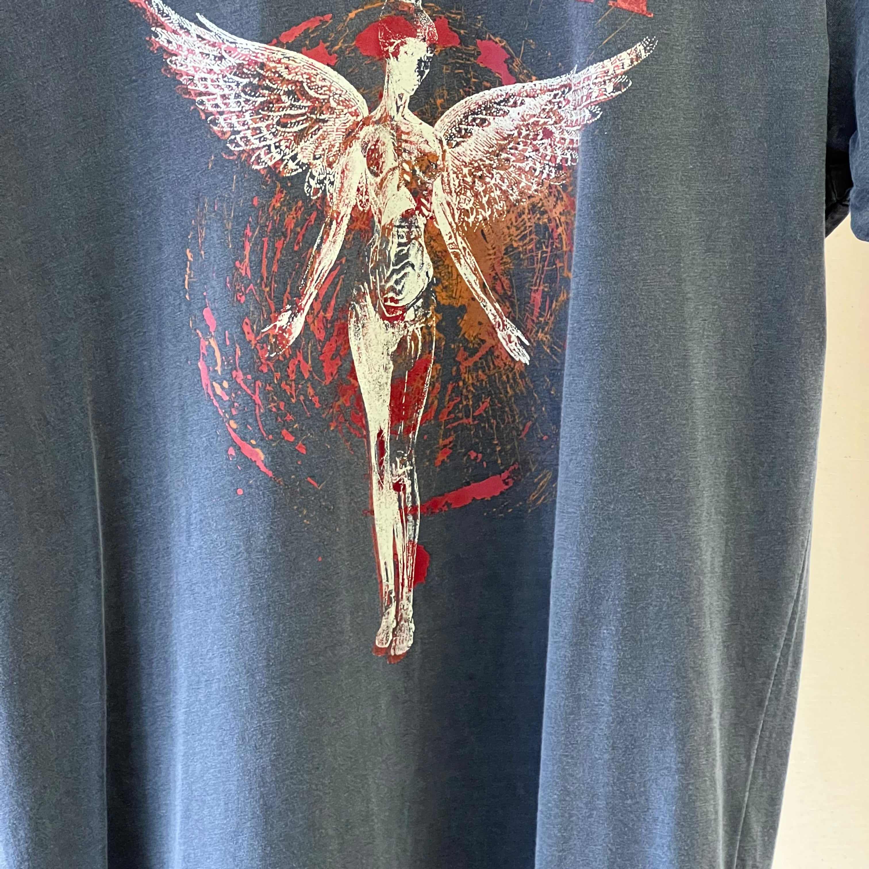 Gray t-shirt with a graphic of a winged figure and red abstract design.