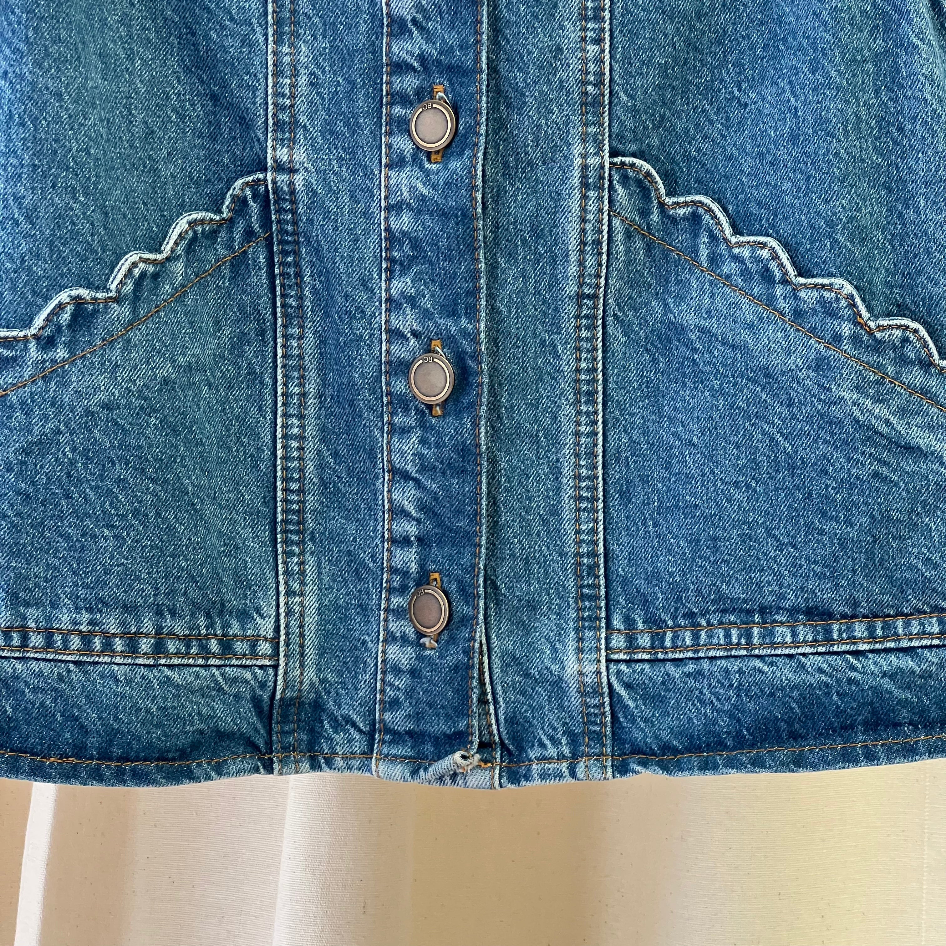 Close-up of a blue denim jacket with button details on a mannequin.