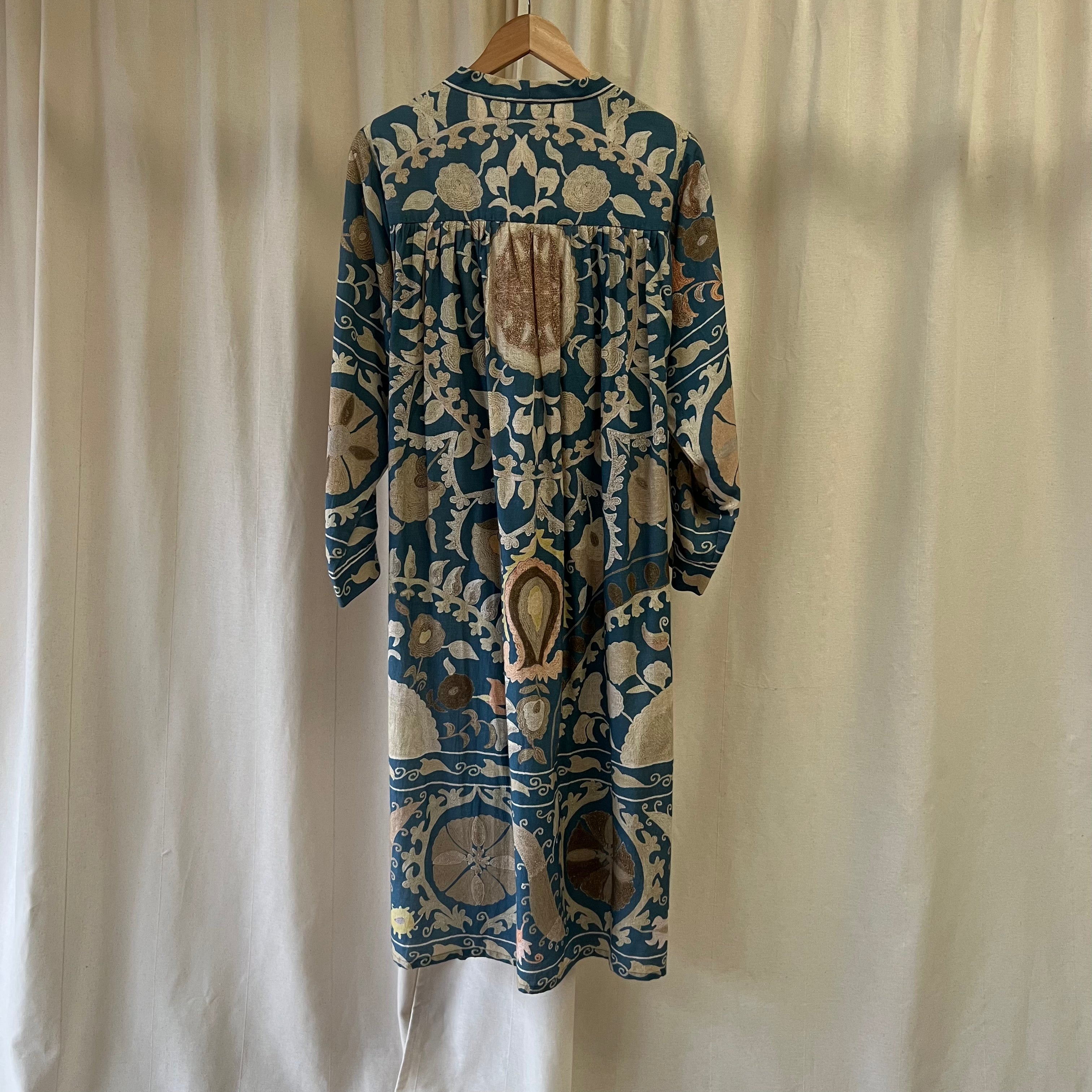 Long-sleeve dress with intricate blue and beige pattern on a hanger against a plain background