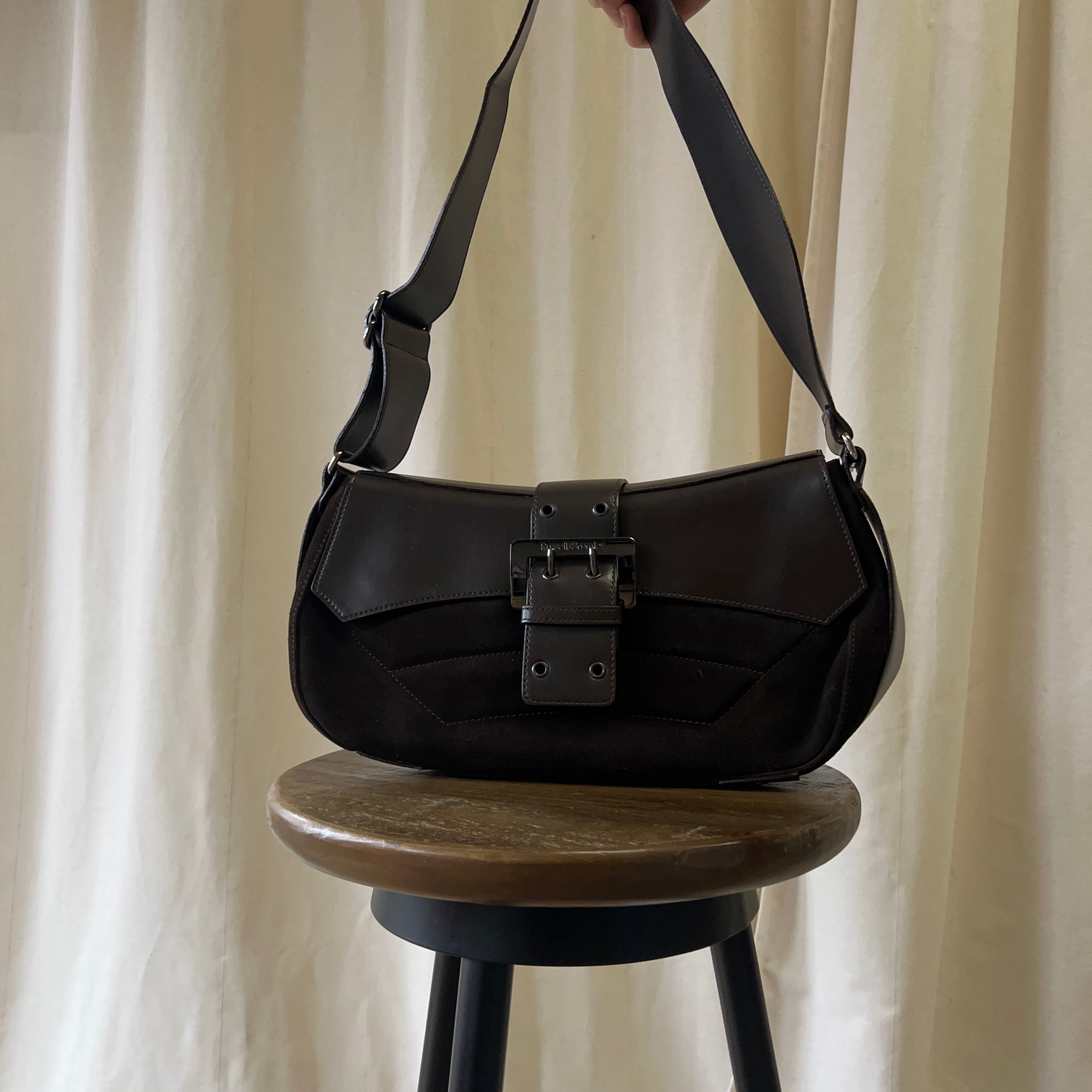 Black handbag on a wooden stool with a neutral background