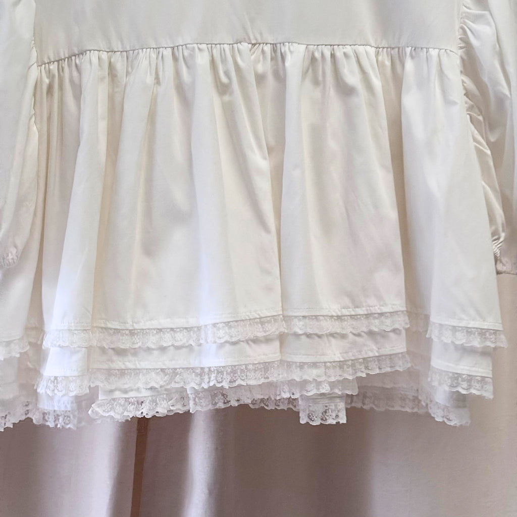 Close-up of a white lace-trimmed dress on a plain background