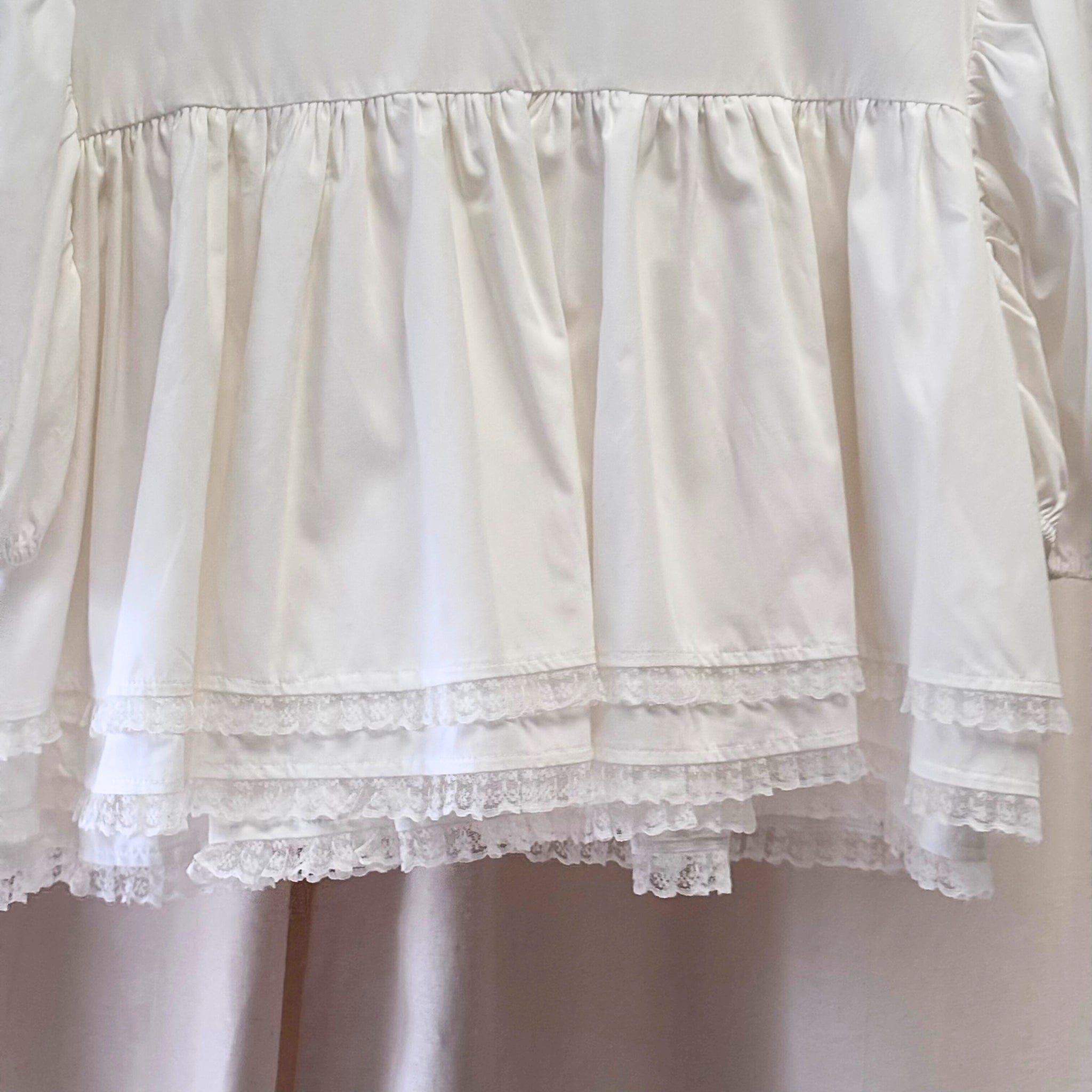 Close-up of a white lace-trimmed dress on a plain background