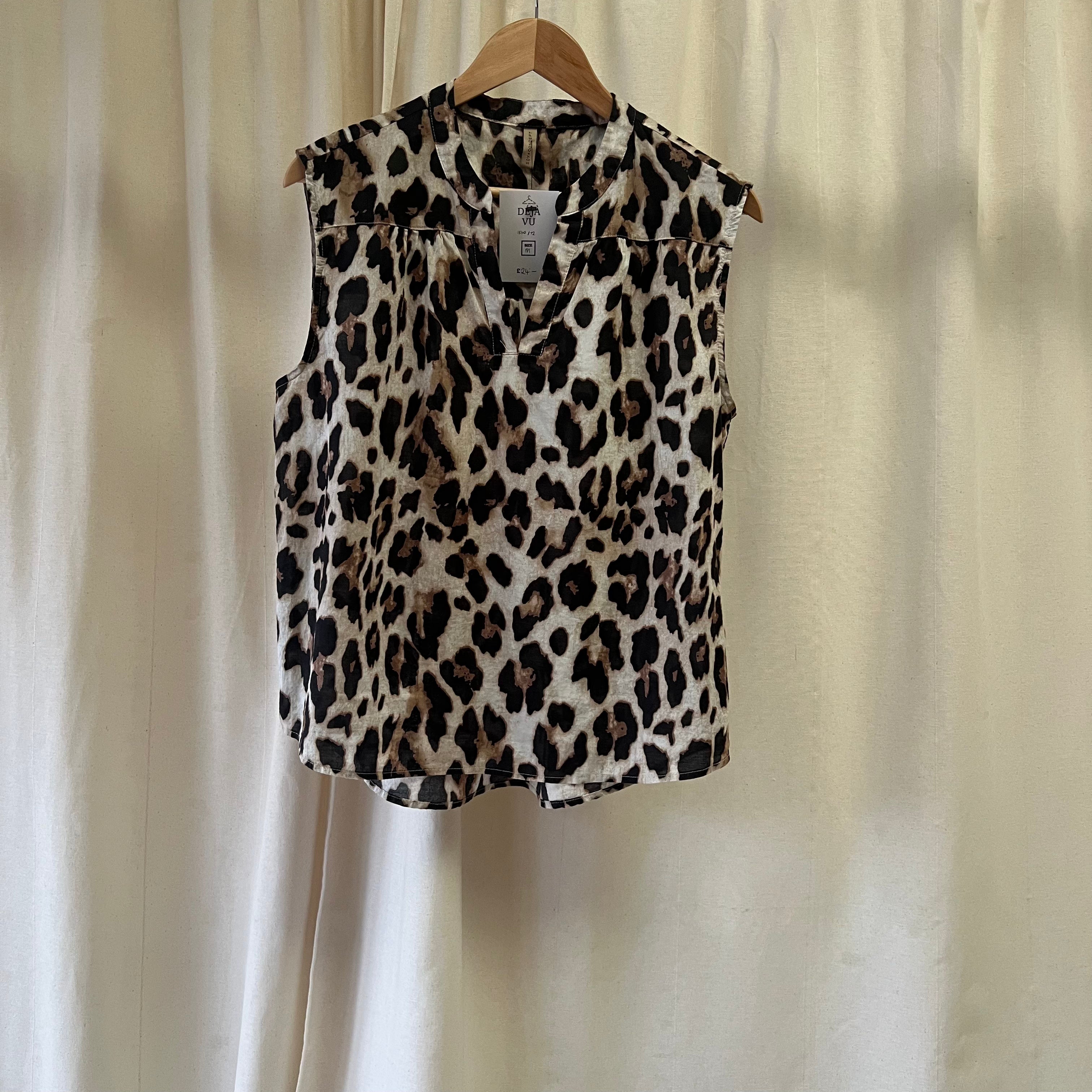 Leopard print sleeveless top on a hanger against a beige curtain background