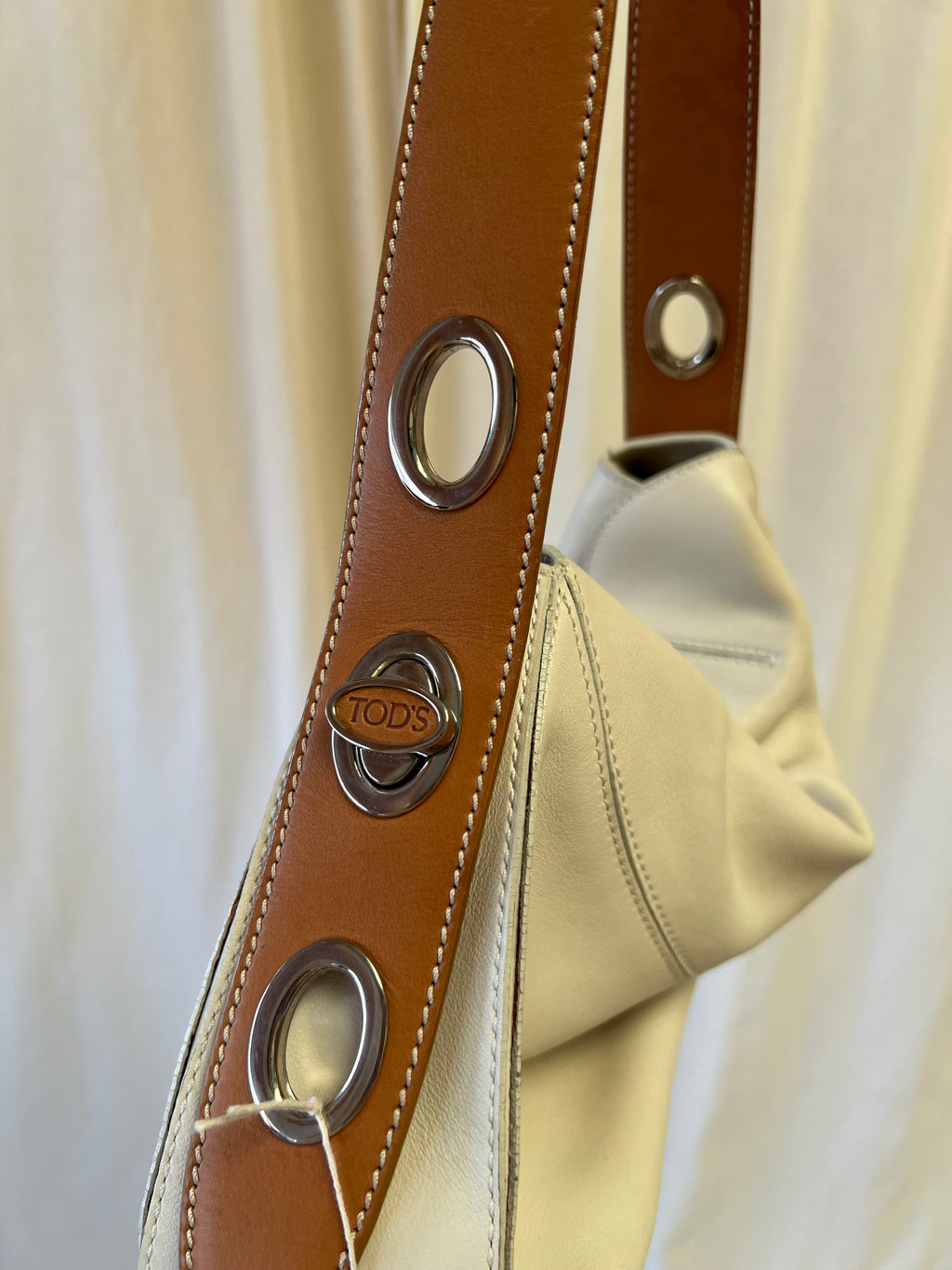 Close-up of a brown leather strap with metal eyelets on a beige background