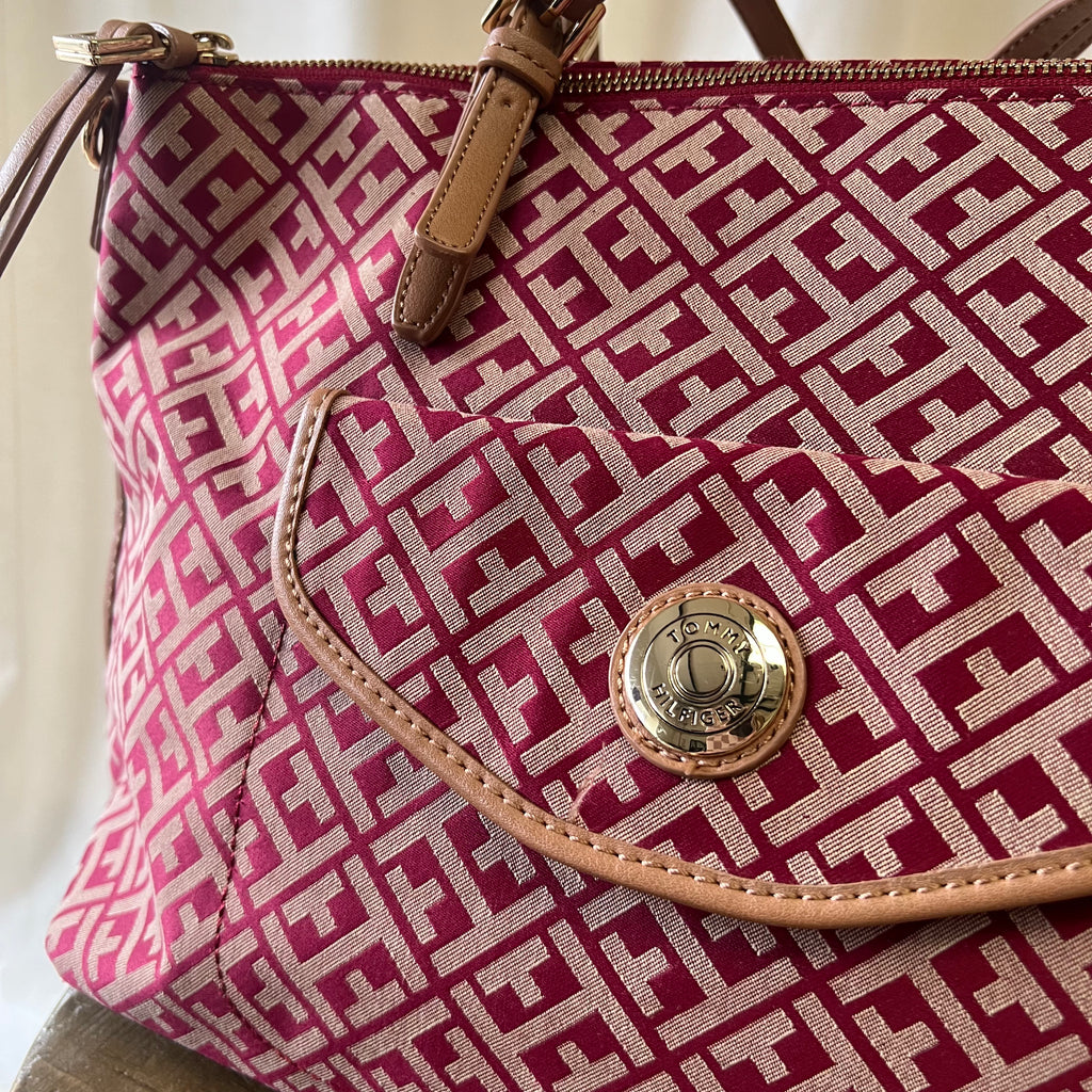 Red and white patterned handbag with gold emblem on a neutral background