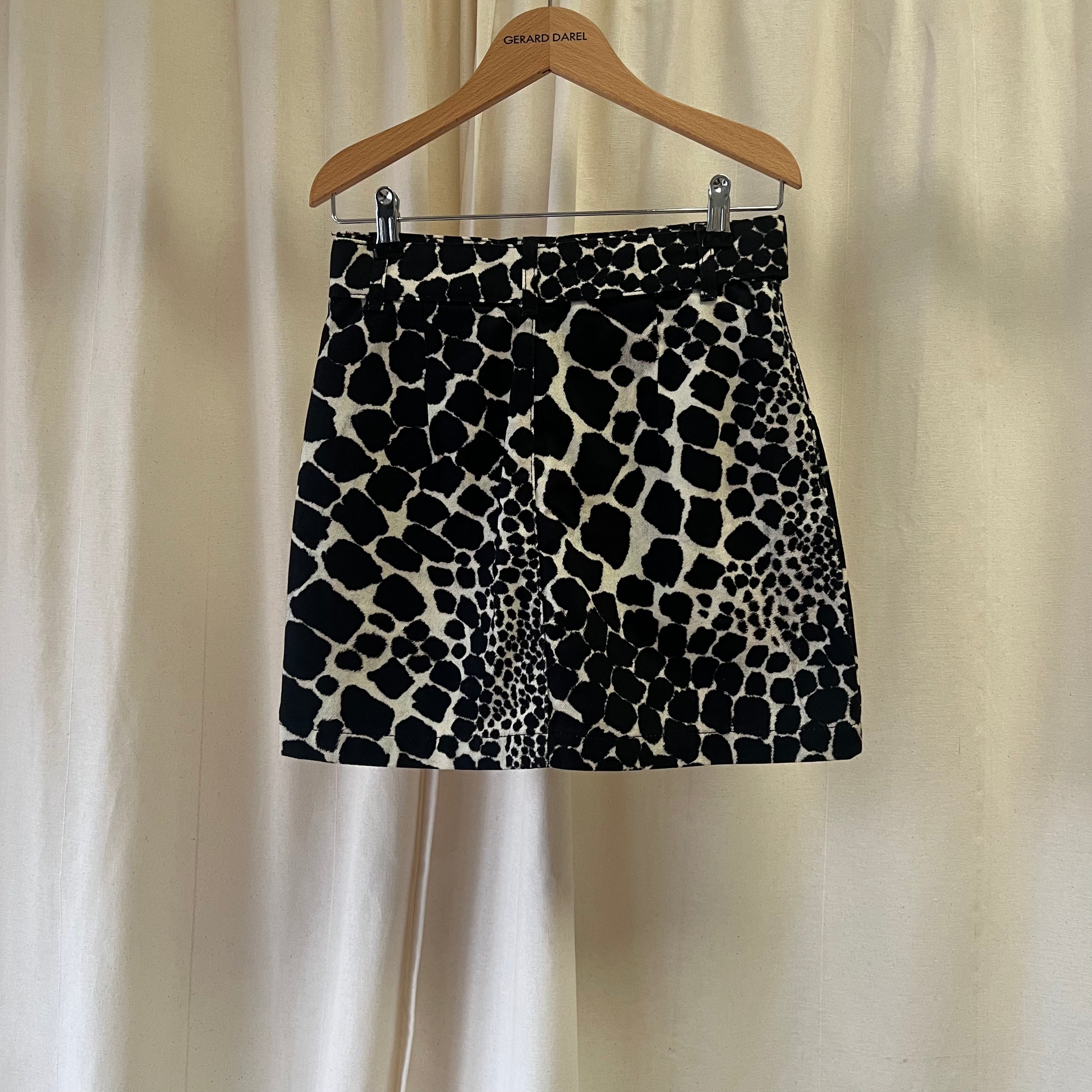 Black and white patterned skirt on a hanger against a beige curtain background