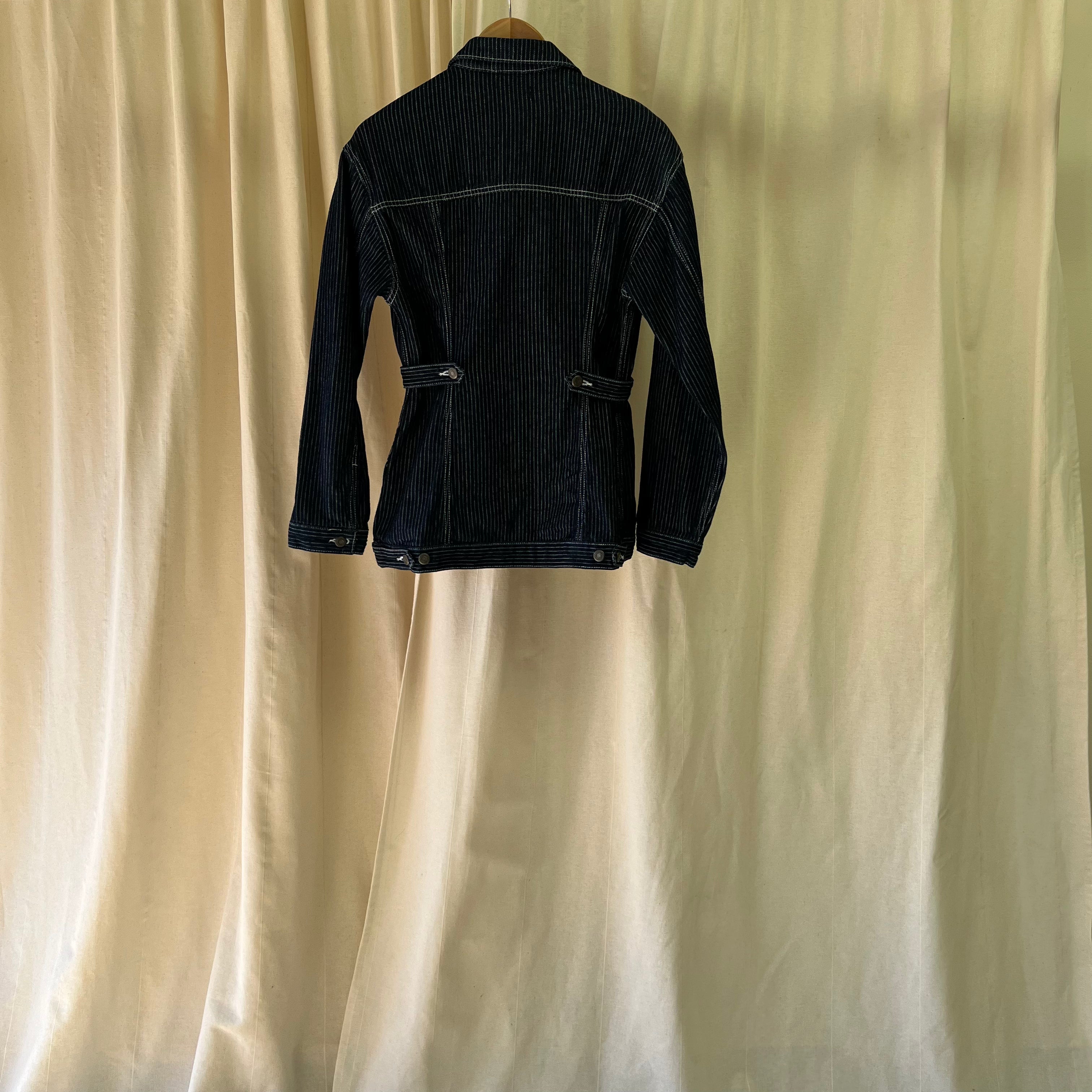 Black jacket on a hanger against a beige curtain background