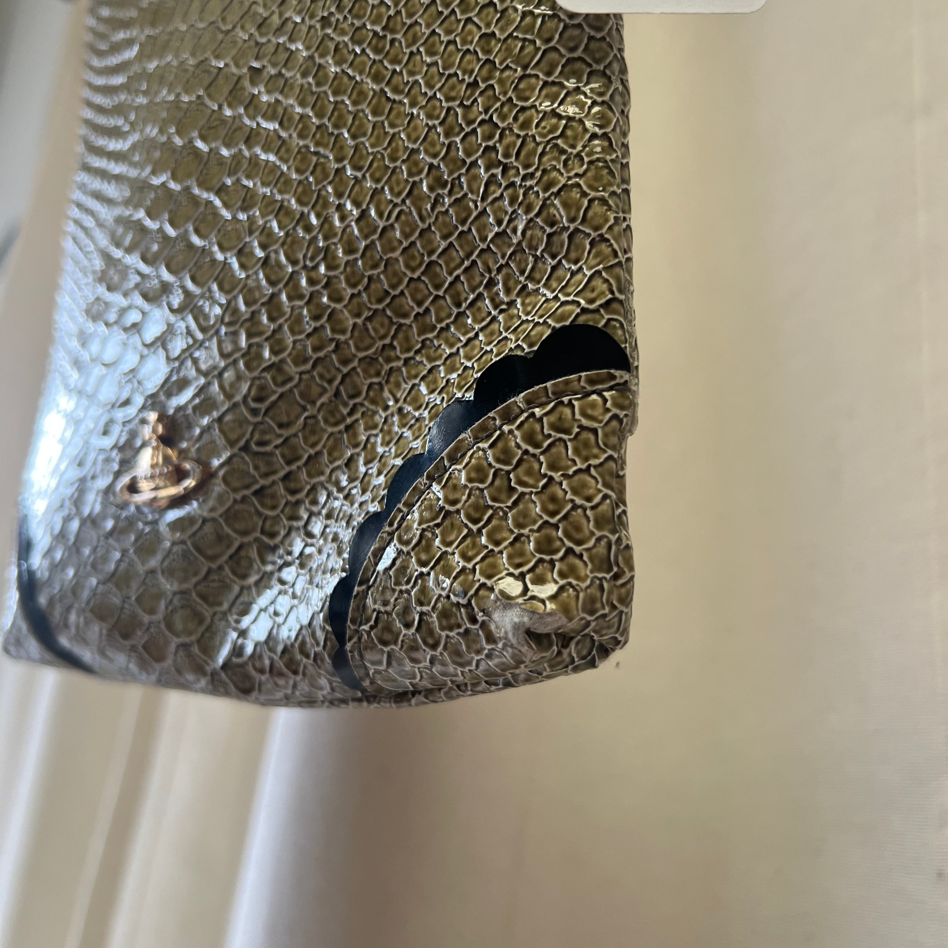 Snakeskin pouch with a brand logo on a beige background