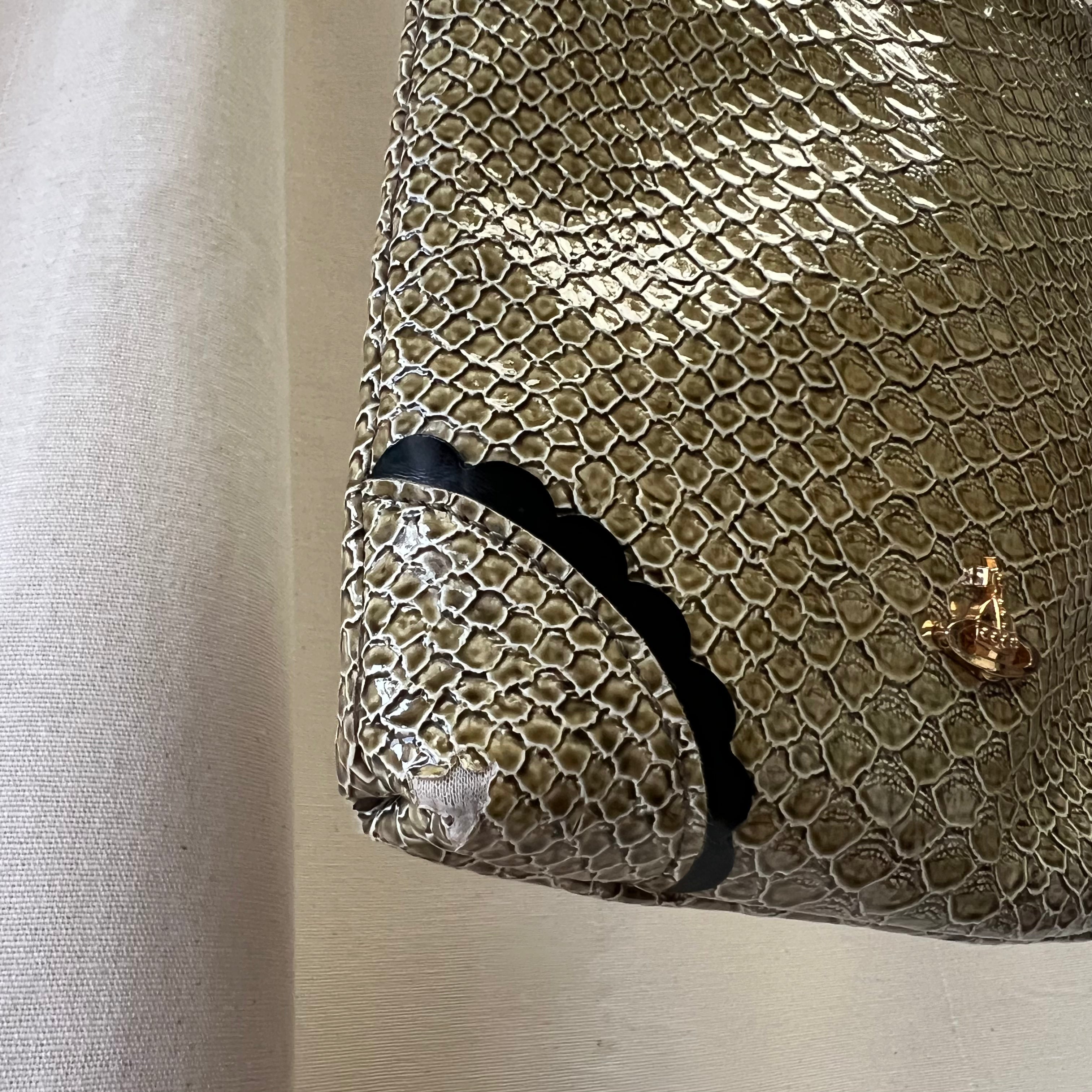 Snakeskin textured handbag with a black strap on a neutral background